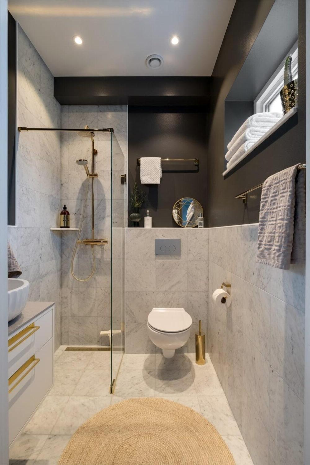 Modern narrow bathroom with gray marble tiles and dark accent wall