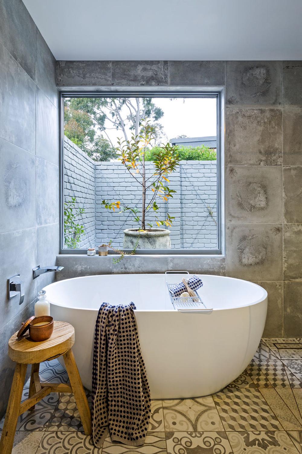 Narrow bathroom centered around a luxurious freestanding oval bathtub and natural lighting