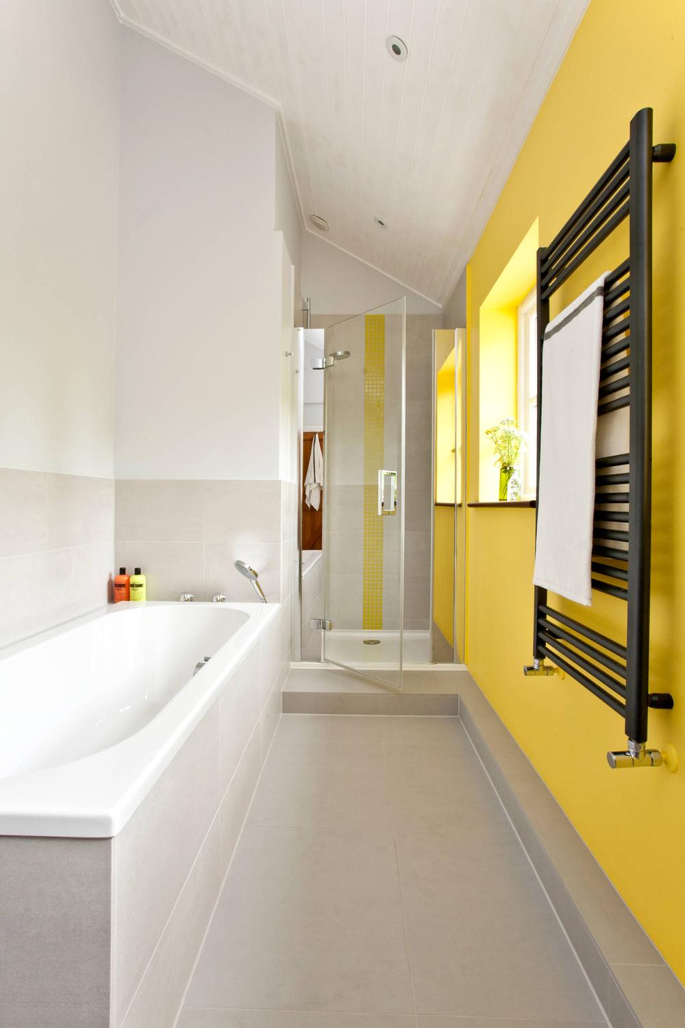 Narrow bathroom featuring a yellow accent wall and modern fixtures