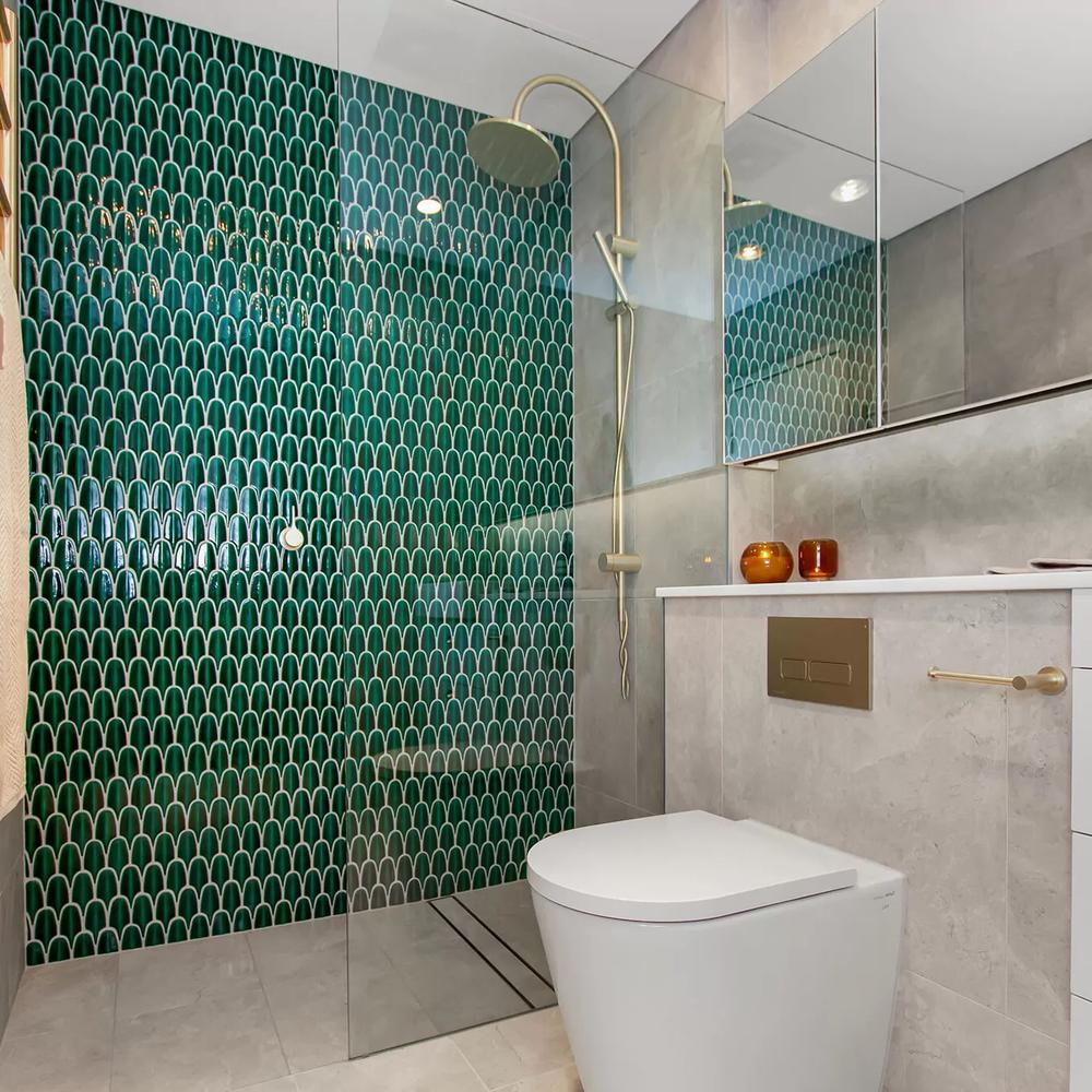 Narrow bathroom featuring bold patterned tiles and a gold shower fixture