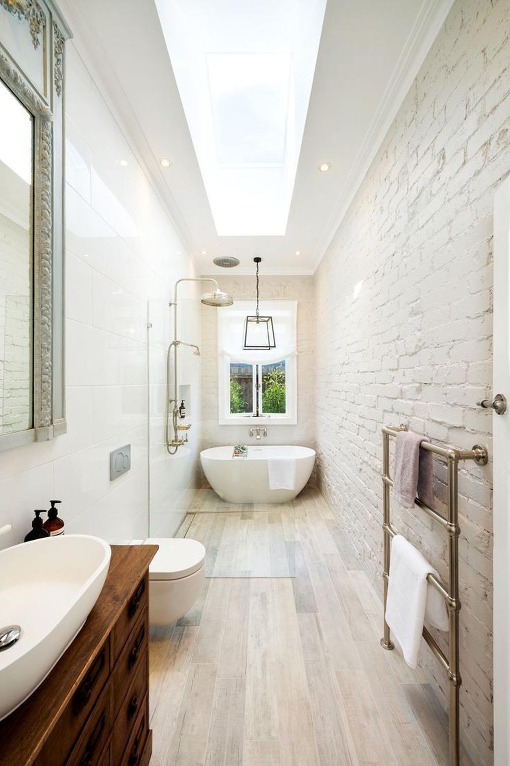 Bright narrow bathroom with white walls and wooden vanities
