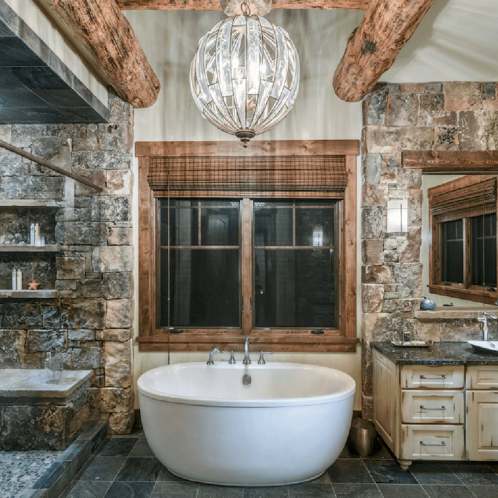 A rustic modern bathroom featuring a freestanding tub and large windows for natural light