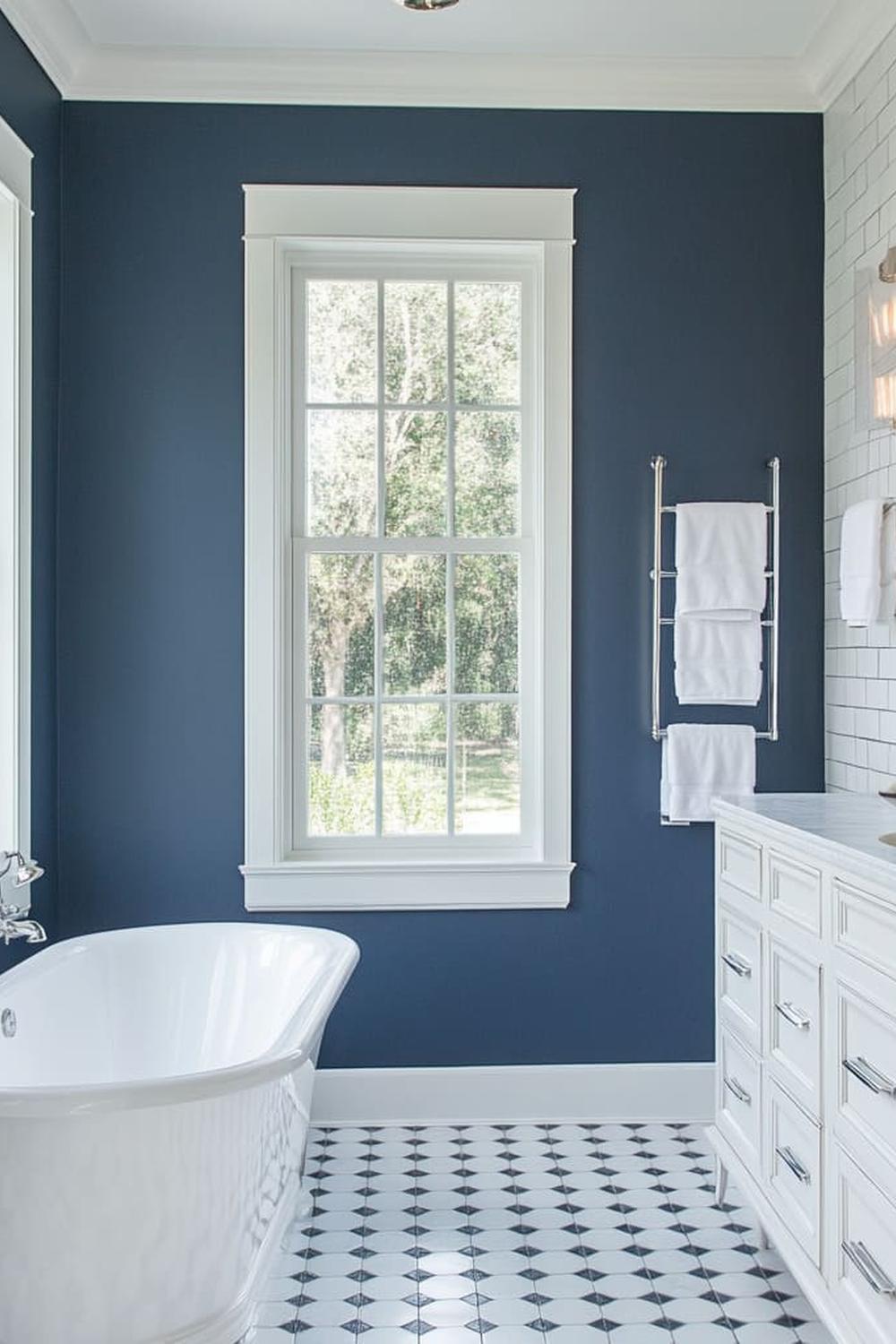 Baño con paredes azul marino y bañera blanca en un diseño moderno