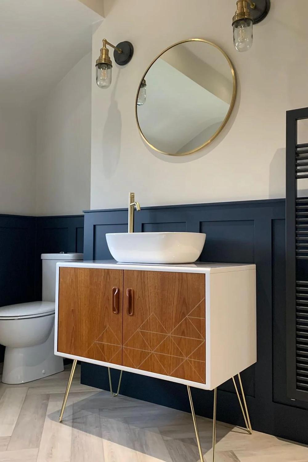 Baño moderno en azul marino con acabados en amarillo dorado y muebles funcionales