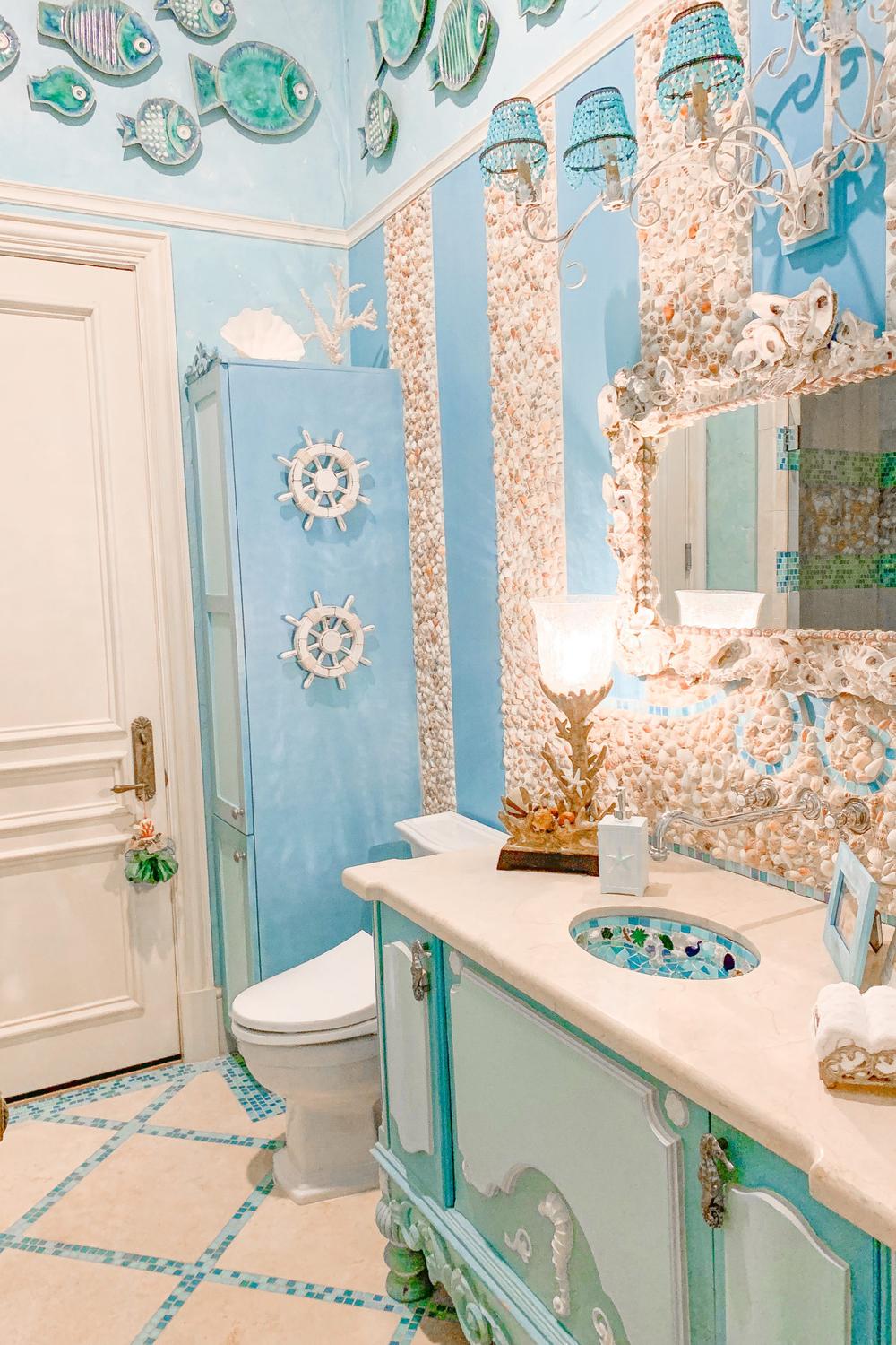 A nautical-themed bathroom featuring soft blue walls and decorative fish sculptures.