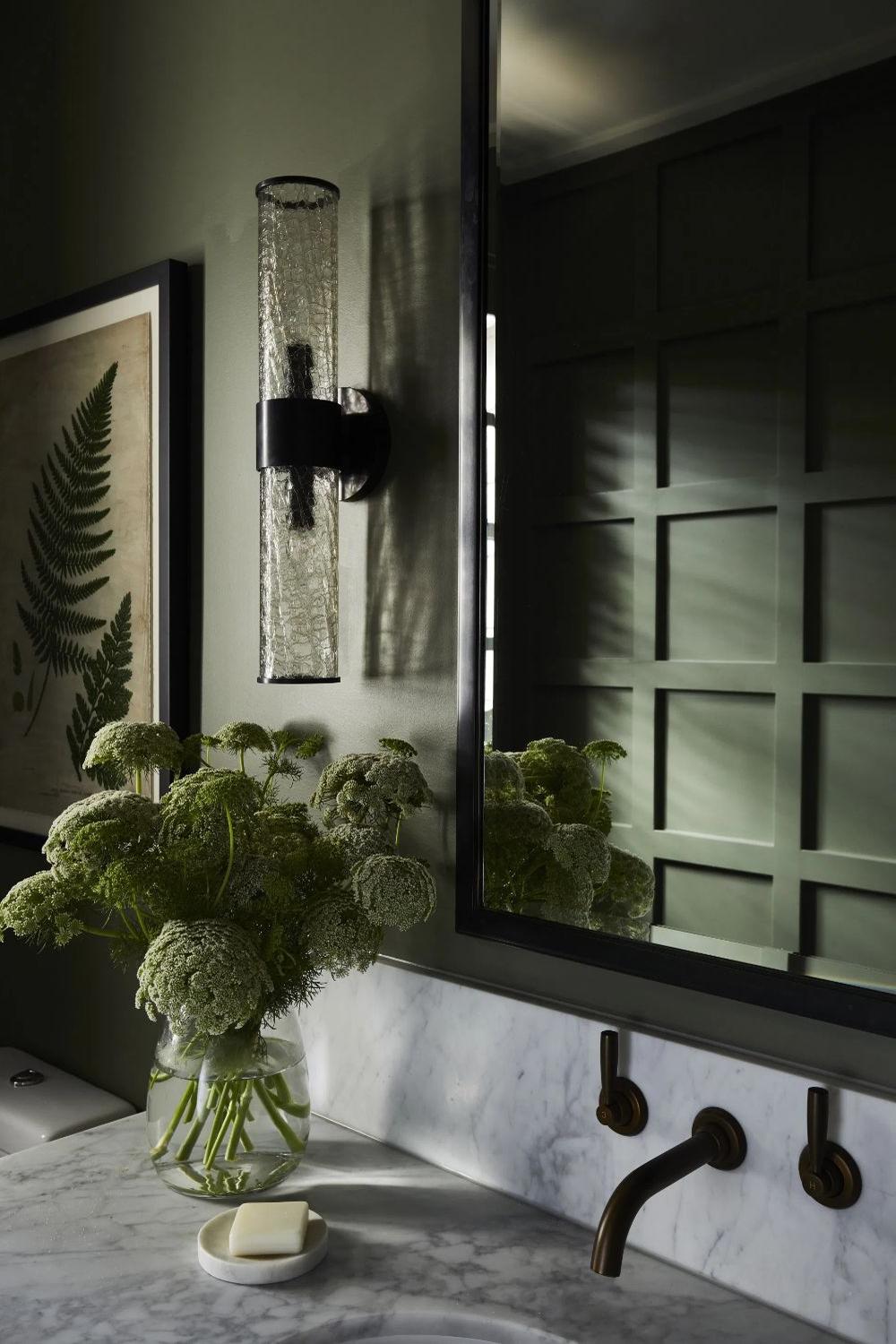A bathroom with olive green features and decorative wall art.