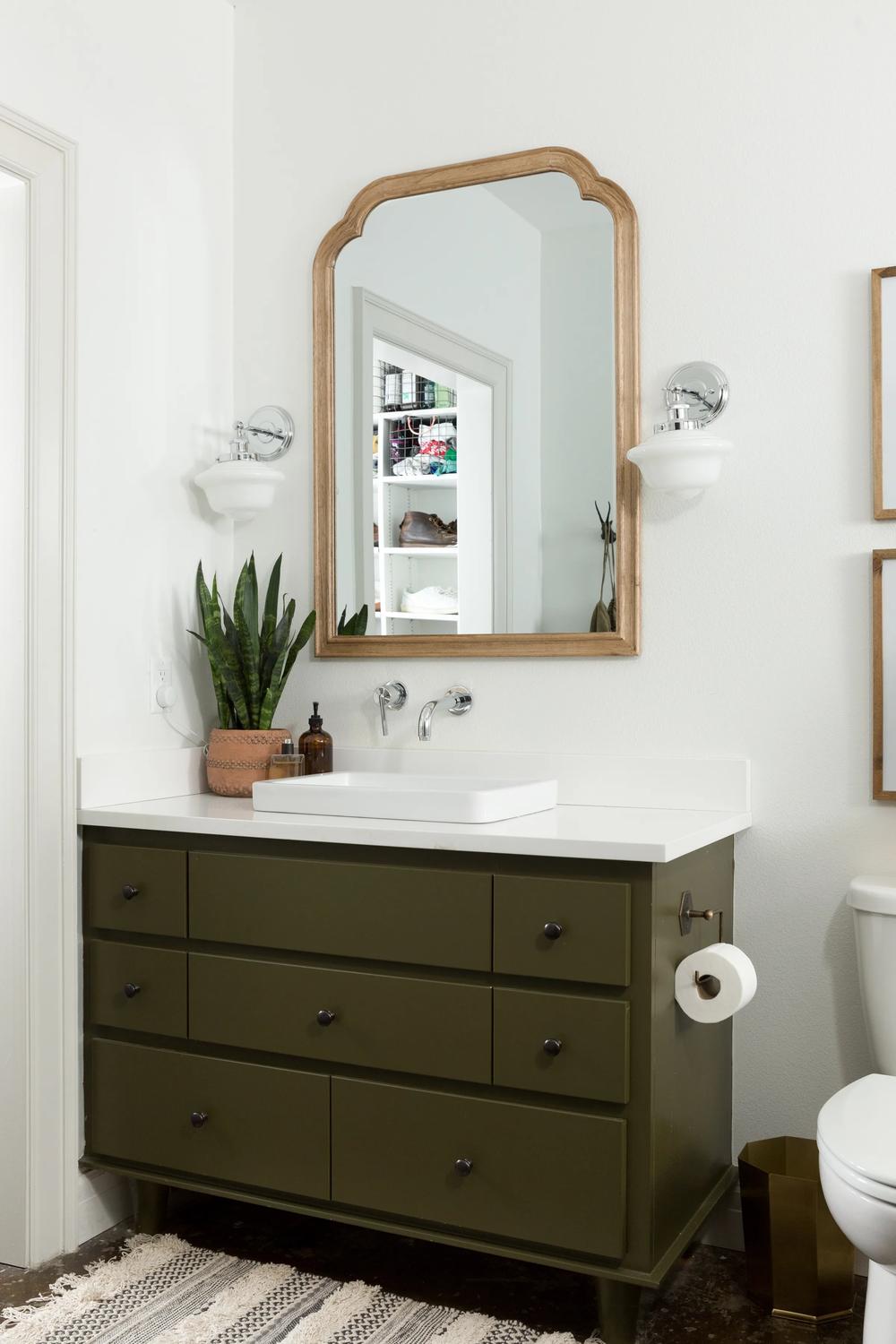 A fresh, airy bathroom with olive green accents and decorative elements.