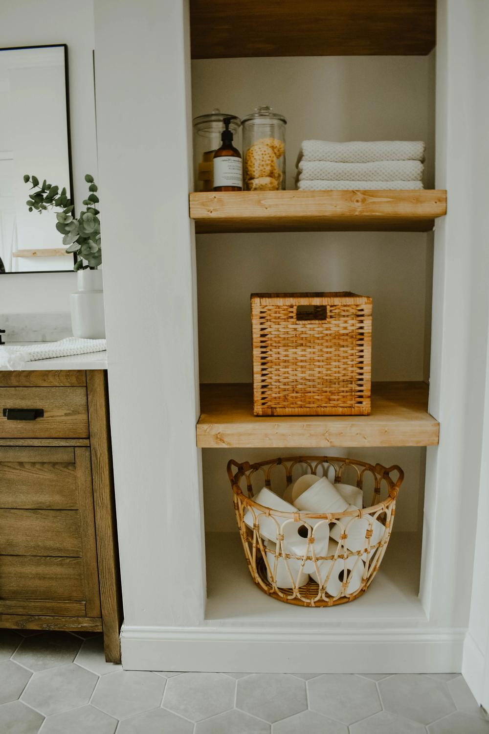 Estantes de madera clara con elementos decorativos y funcionales en un baño elegante