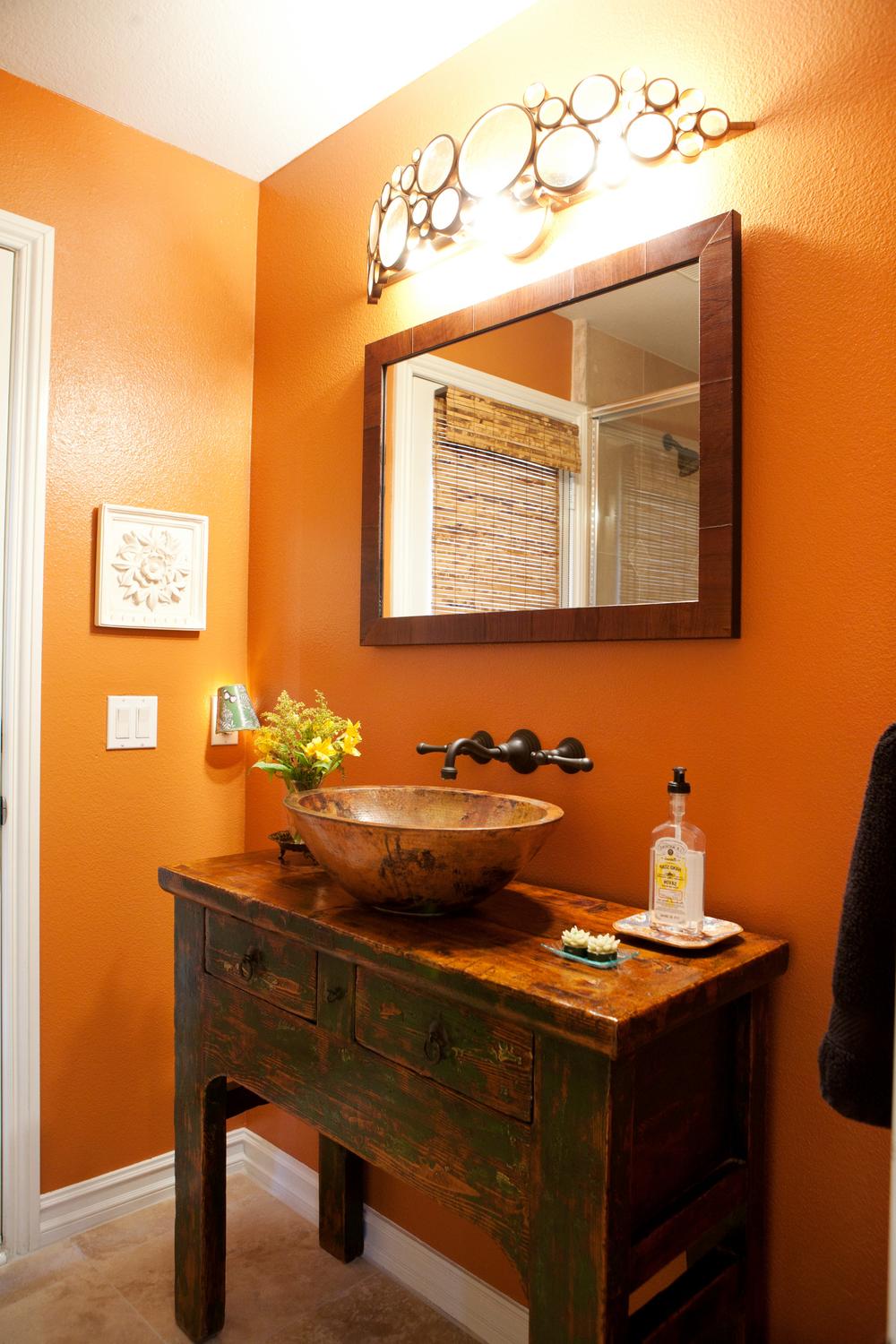 A stylish orange bathroom with a rustic wooden vanity and modern vessel sink.