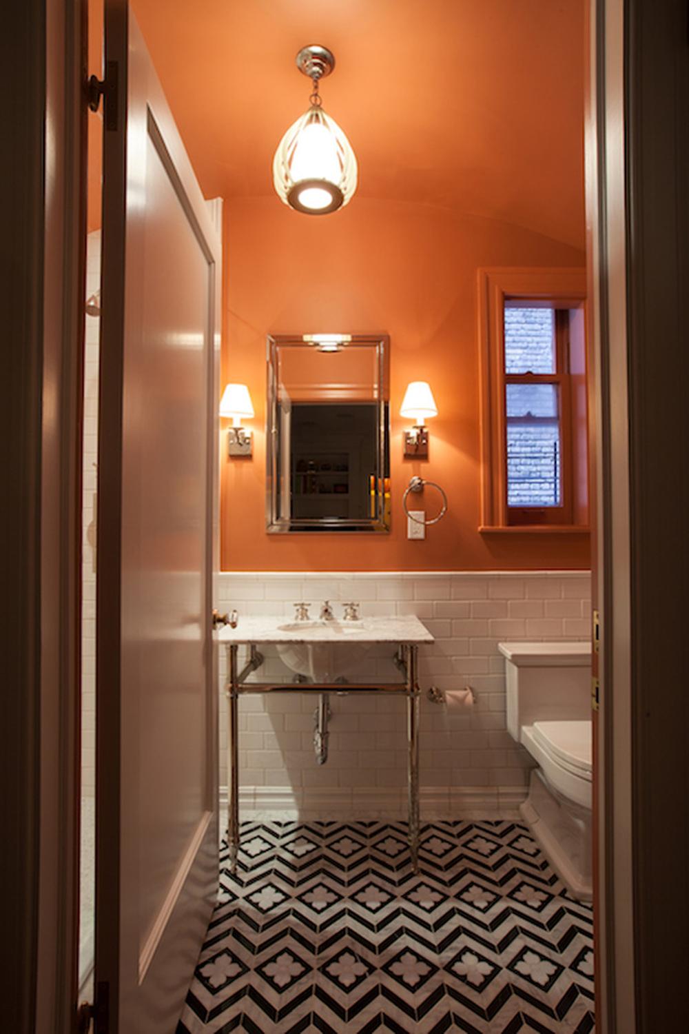 A compact bathroom design showcasing vibrant orange walls and modern elements.