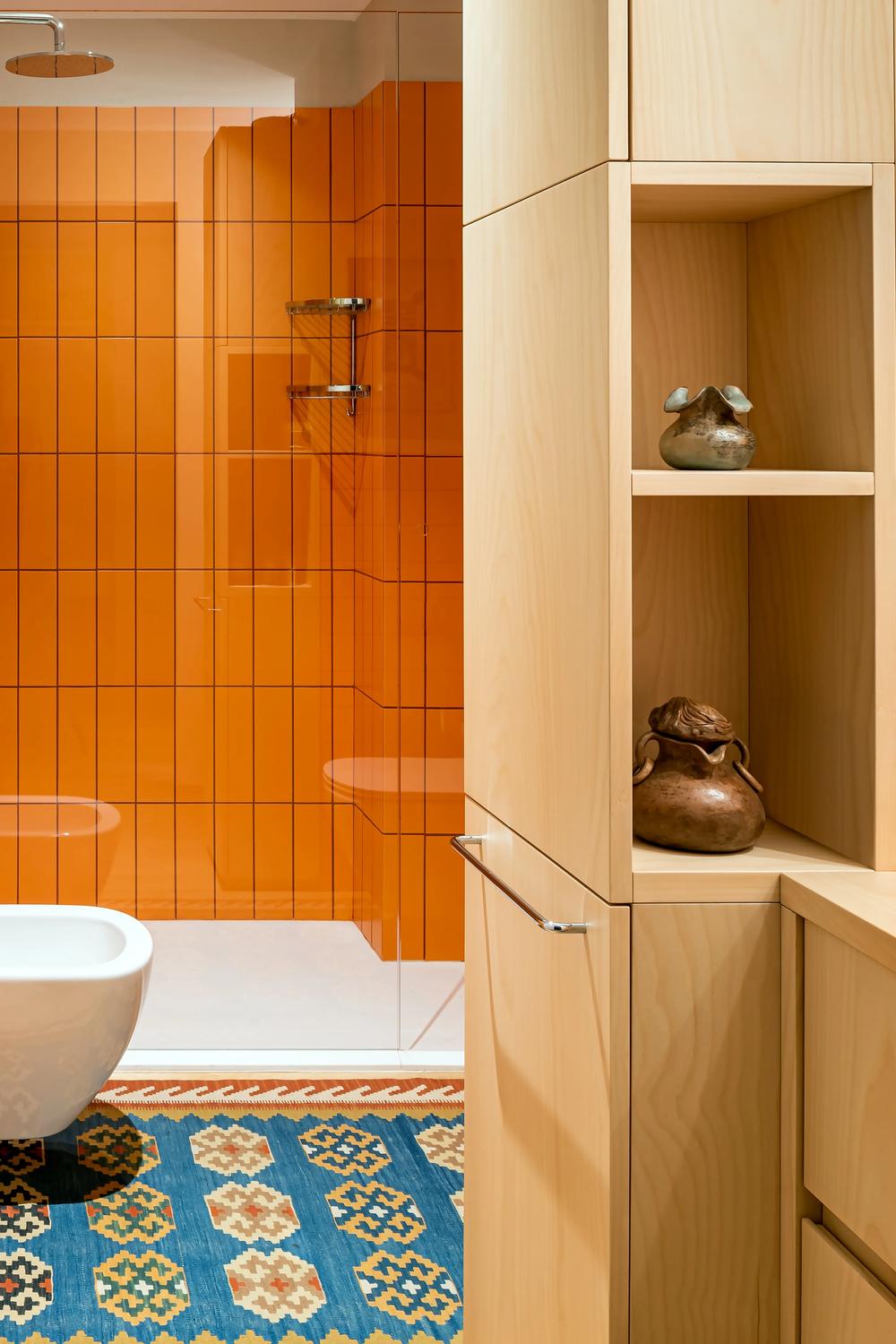 A modern bathroom featuring a sleek design with playful orange tiles and natural elements.