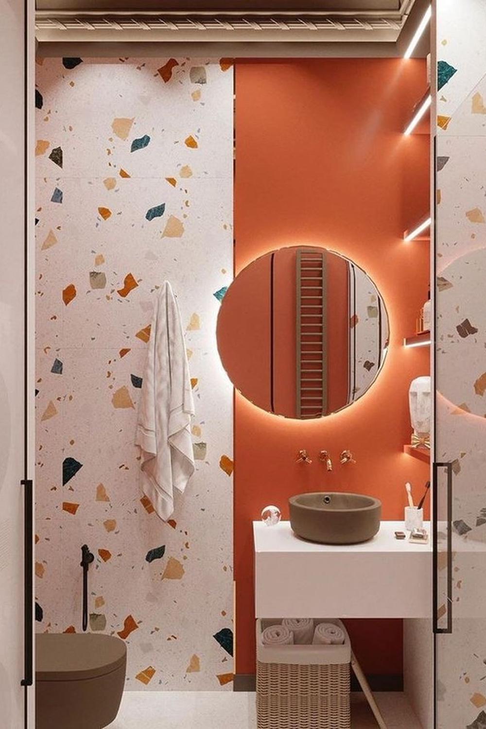 A stylish bathroom showcasing textured orange walls and a reflective circular mirror.