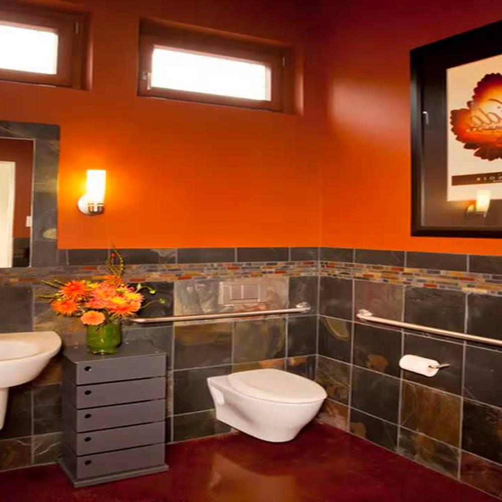 A modern bathroom design with vibrant orange walls, natural light, and stylish accessible features.