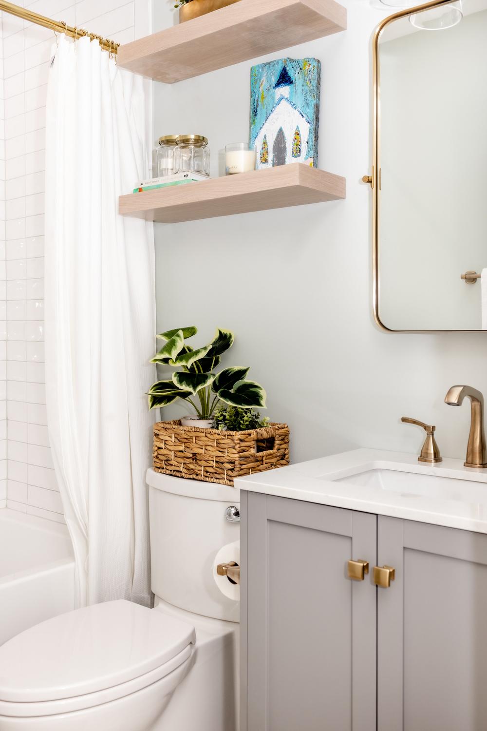 Baño con azulejos blancos y estanterías de madera