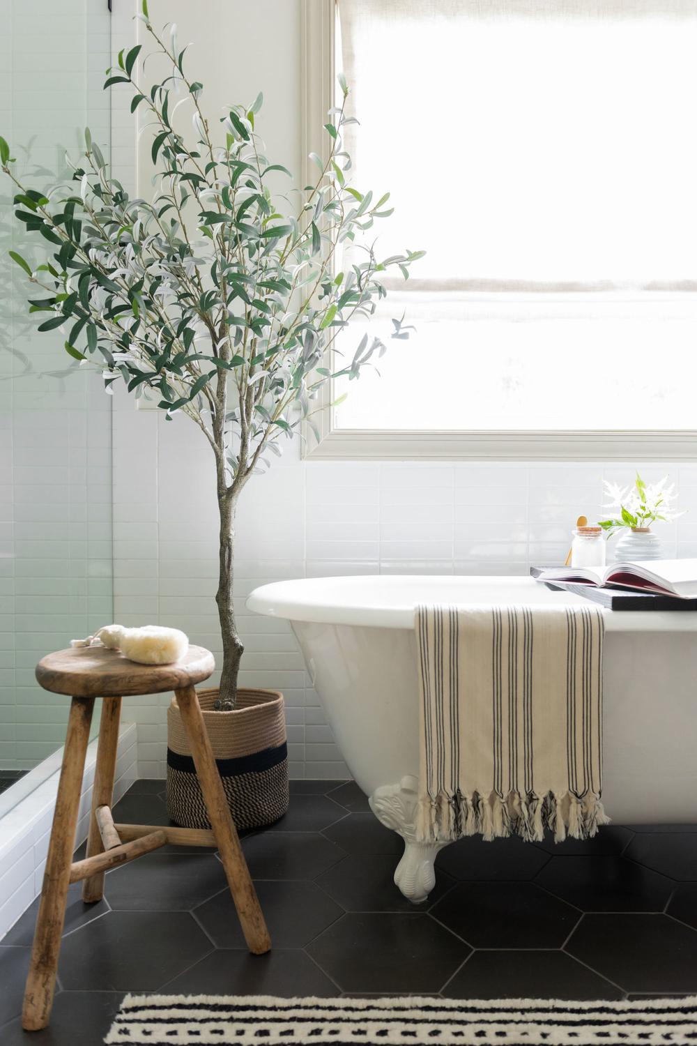 Baño con bañera vintage y árbol natural