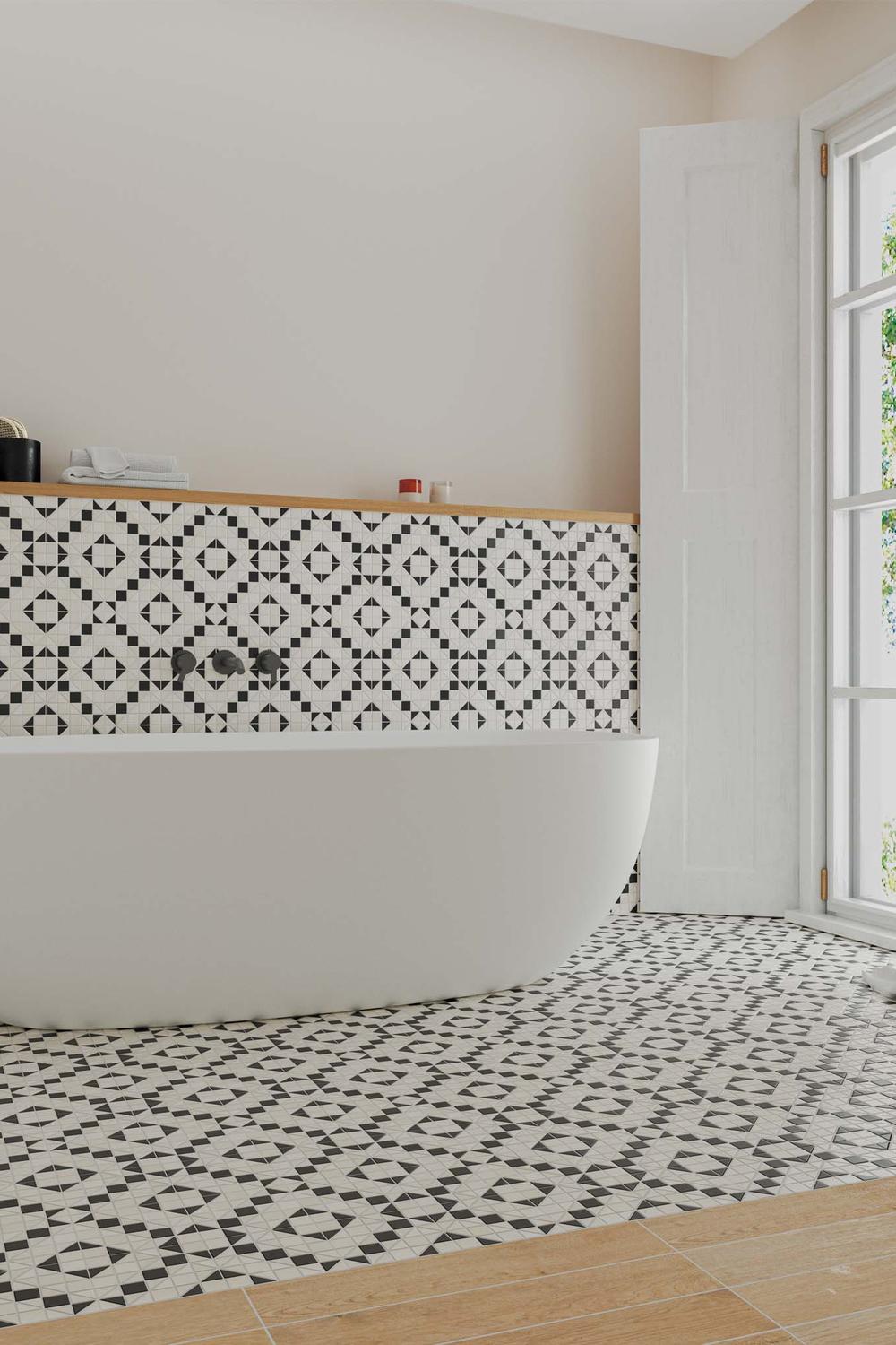 A modern freestanding bathtub against a stylish geometric tile wall.