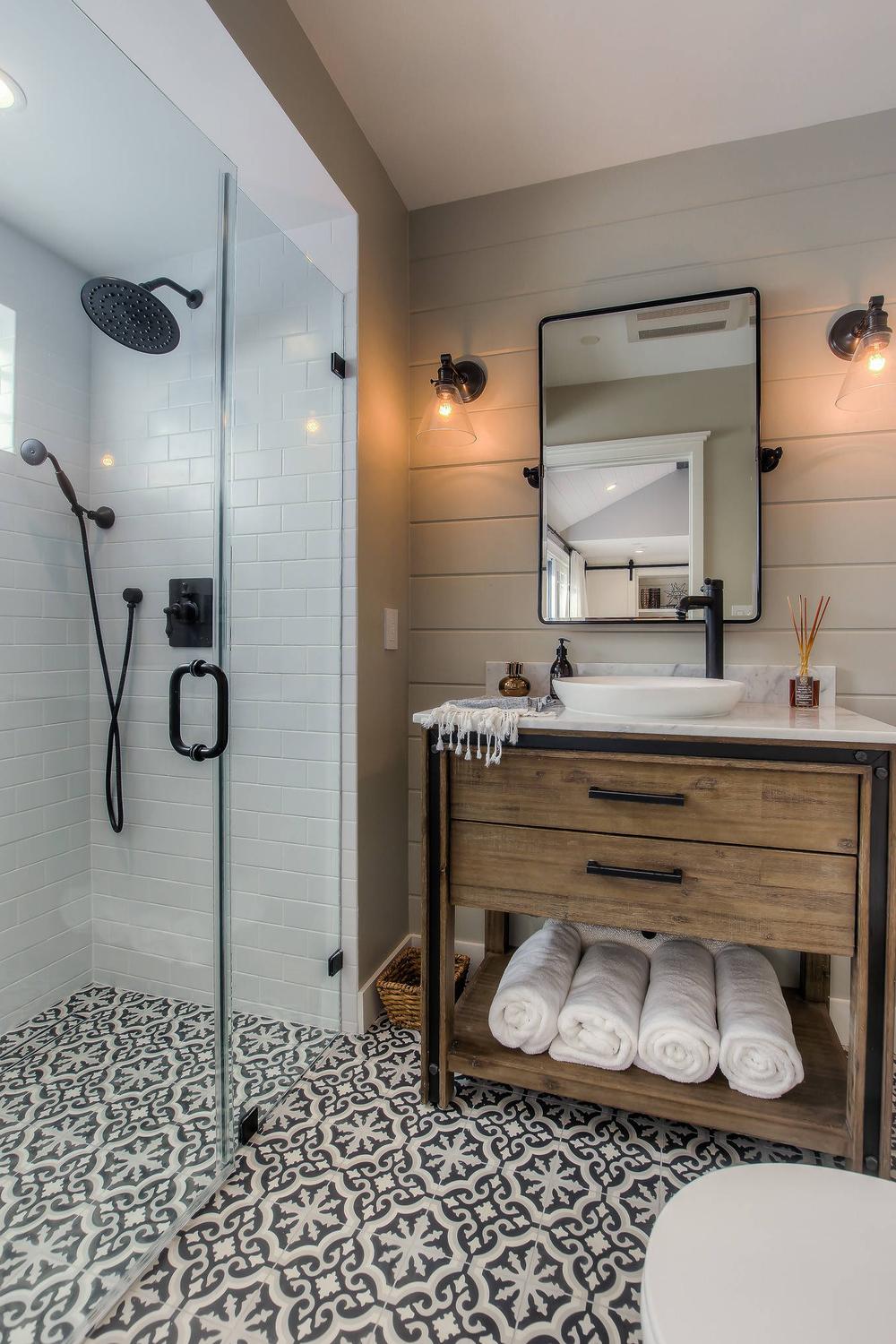 Baño moderno con ducha de cristal y azulejos blancos, creando un ambiente fresco y contemporáneo