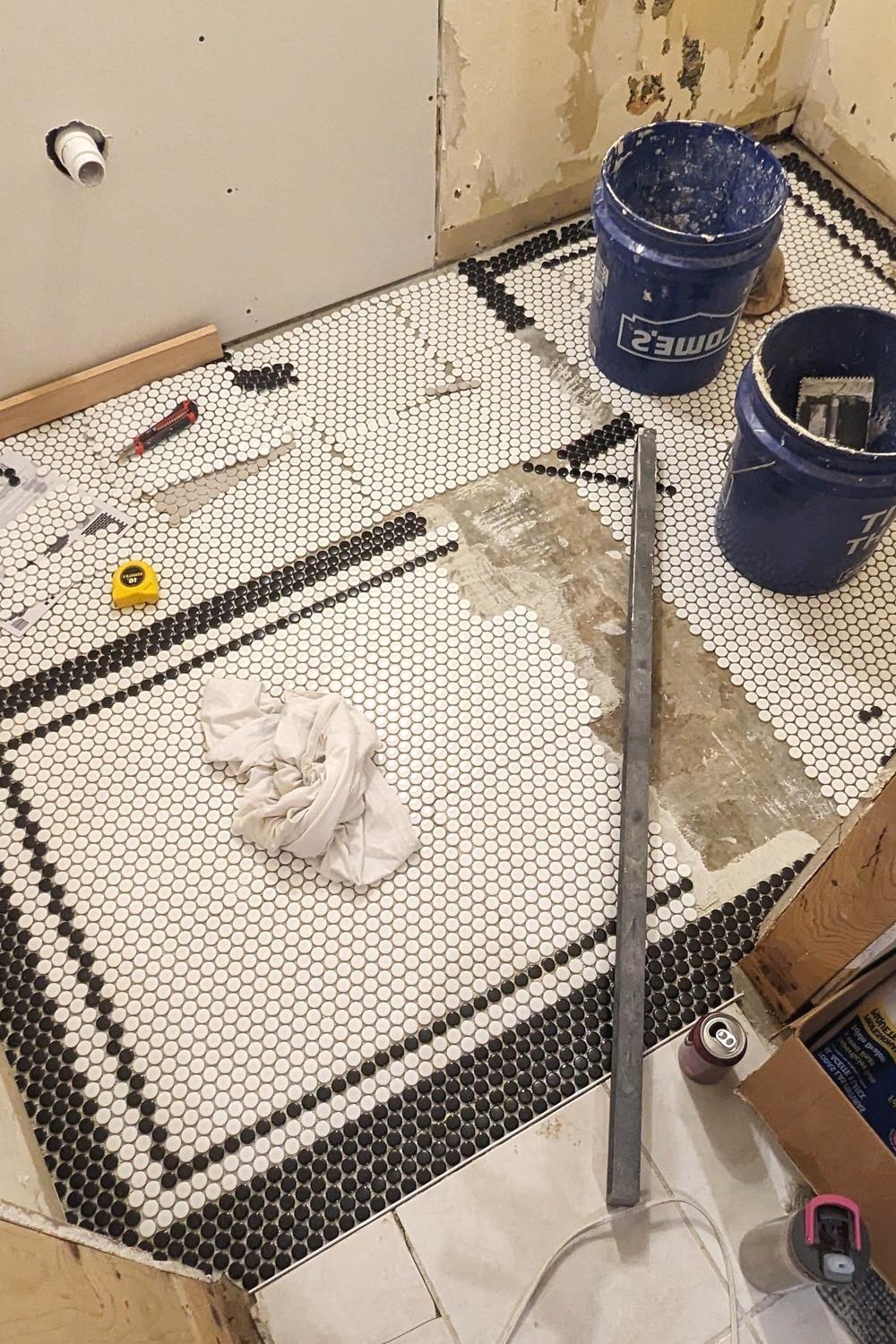 A vintage-style bathroom showcasing black and white penny tiles with a geometric pattern.