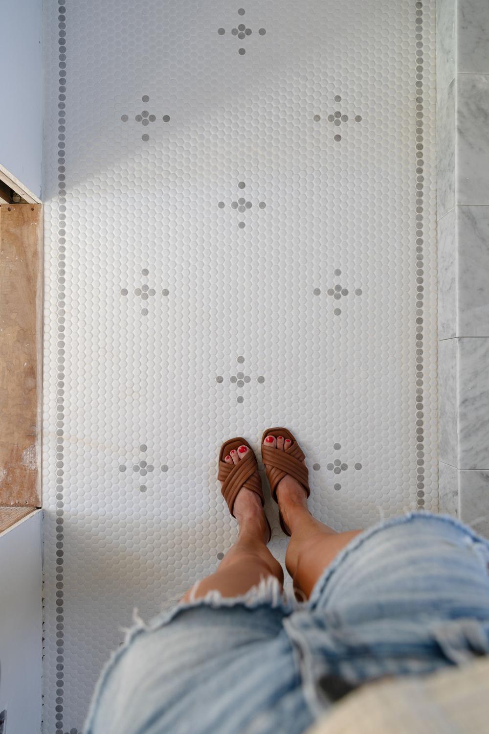 A bathroom with a retro aesthetic highlighted by glossy penny tiles in playful patterns.