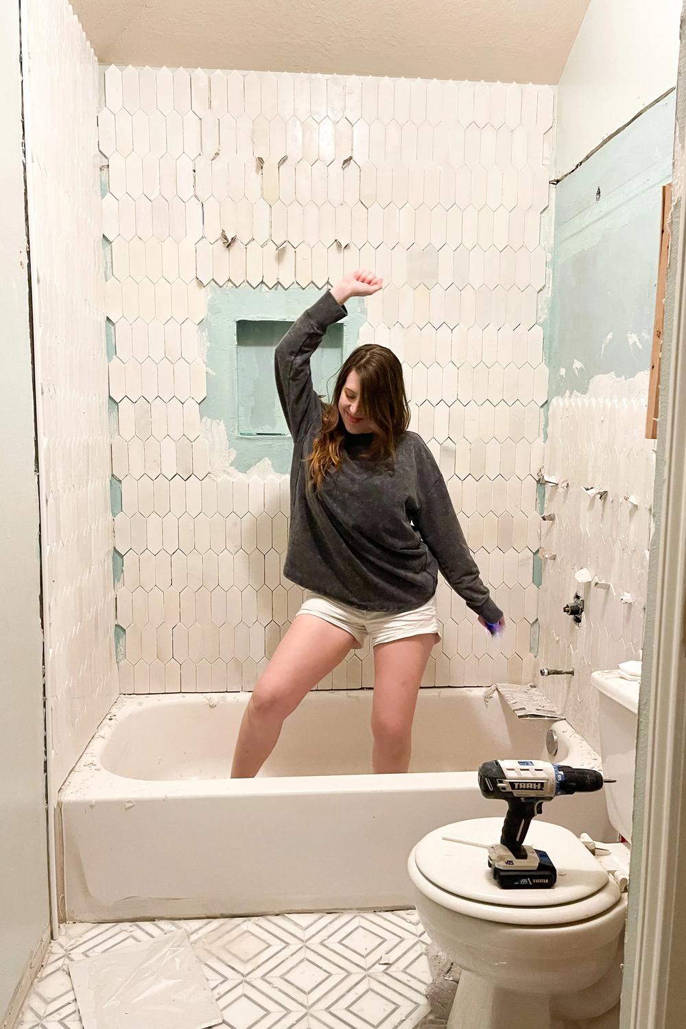 A work-in-progress bathroom showcasing half-finished picket tile walls and playful renovation energy, creating a fun transitional space.