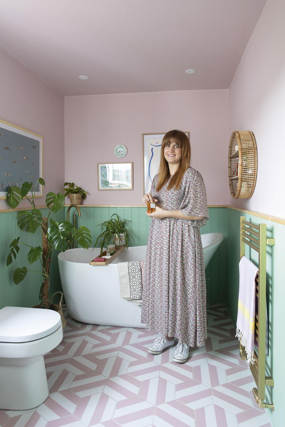 Stylish bathroom featuring soft pink walls and green paneling with geometric tiles