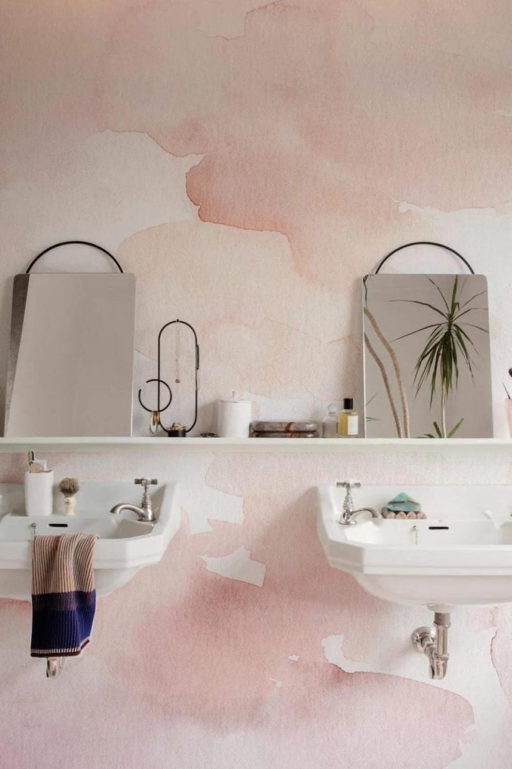 Stylish bathroom featuring soft pink watercolor wallpaper with modern white sinks