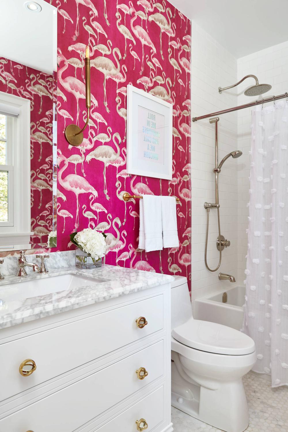Stylish pink bathroom with white flamingo-patterned wallpaper