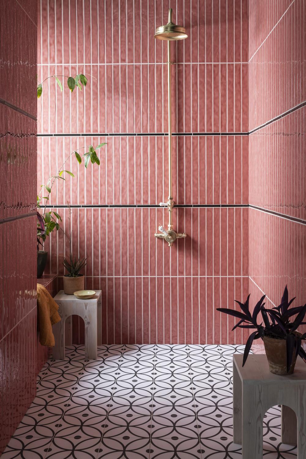 Baño con azulejos rosas brillantes y suelo con patrones geométricos.