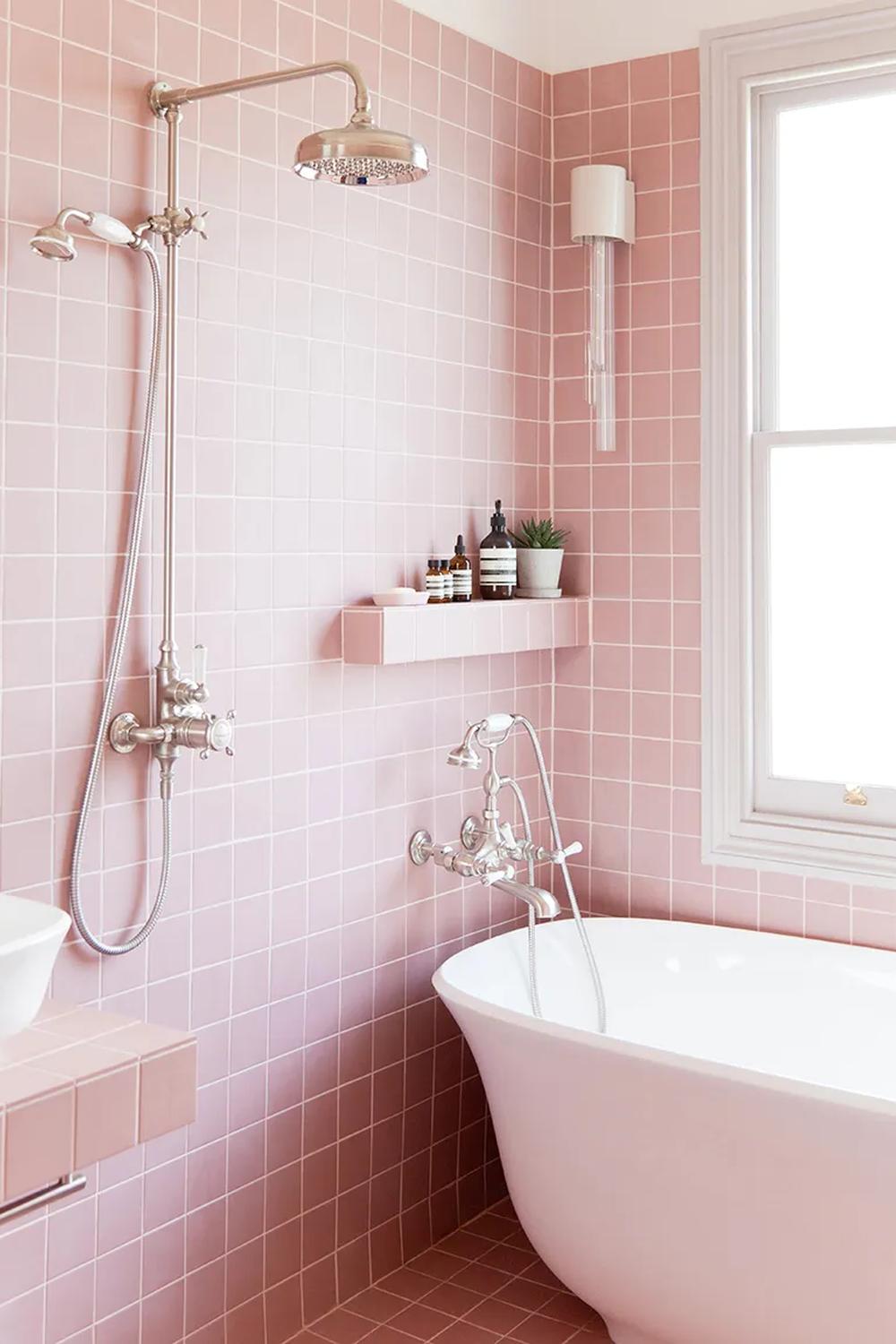 Baño moderno con azulejos rosa y una bañera elegante para un look sofisticado.