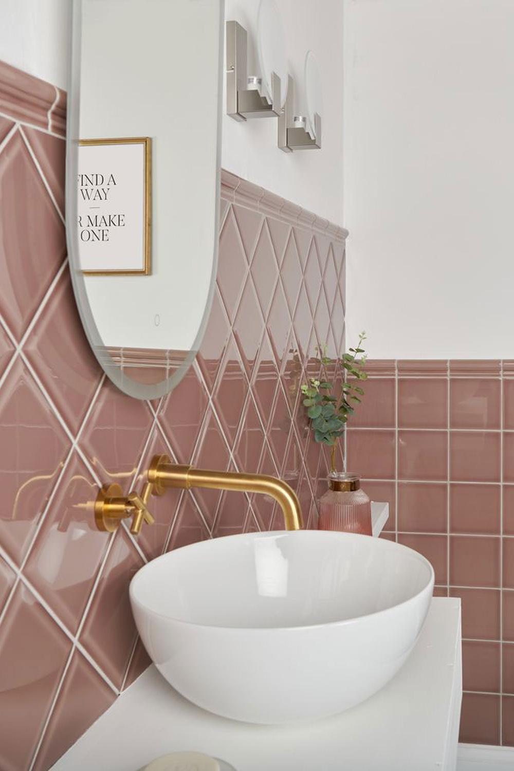 Baño con azulejos rosas y elegantes detalles que crean una atmósfera moderna.
