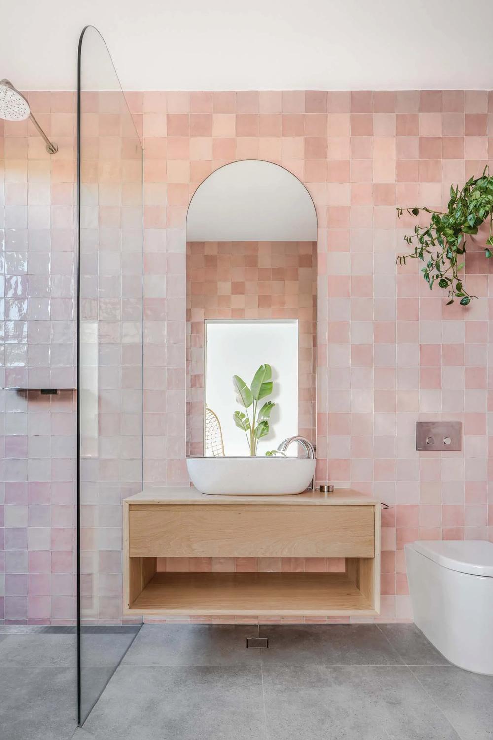 Baño moderno con azulejos rosas en un diseño fresco y funcional.
