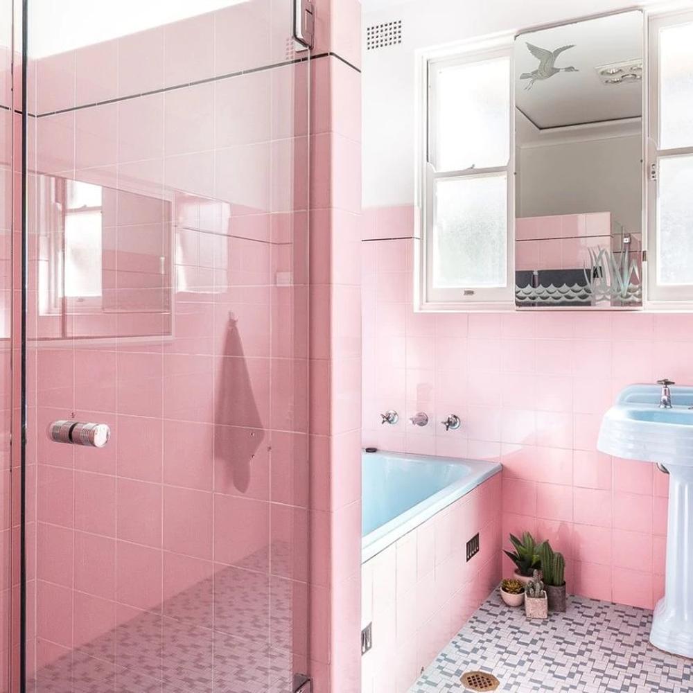 Baño retro con azulejos rosas que ofrecen un aire nostálgico.