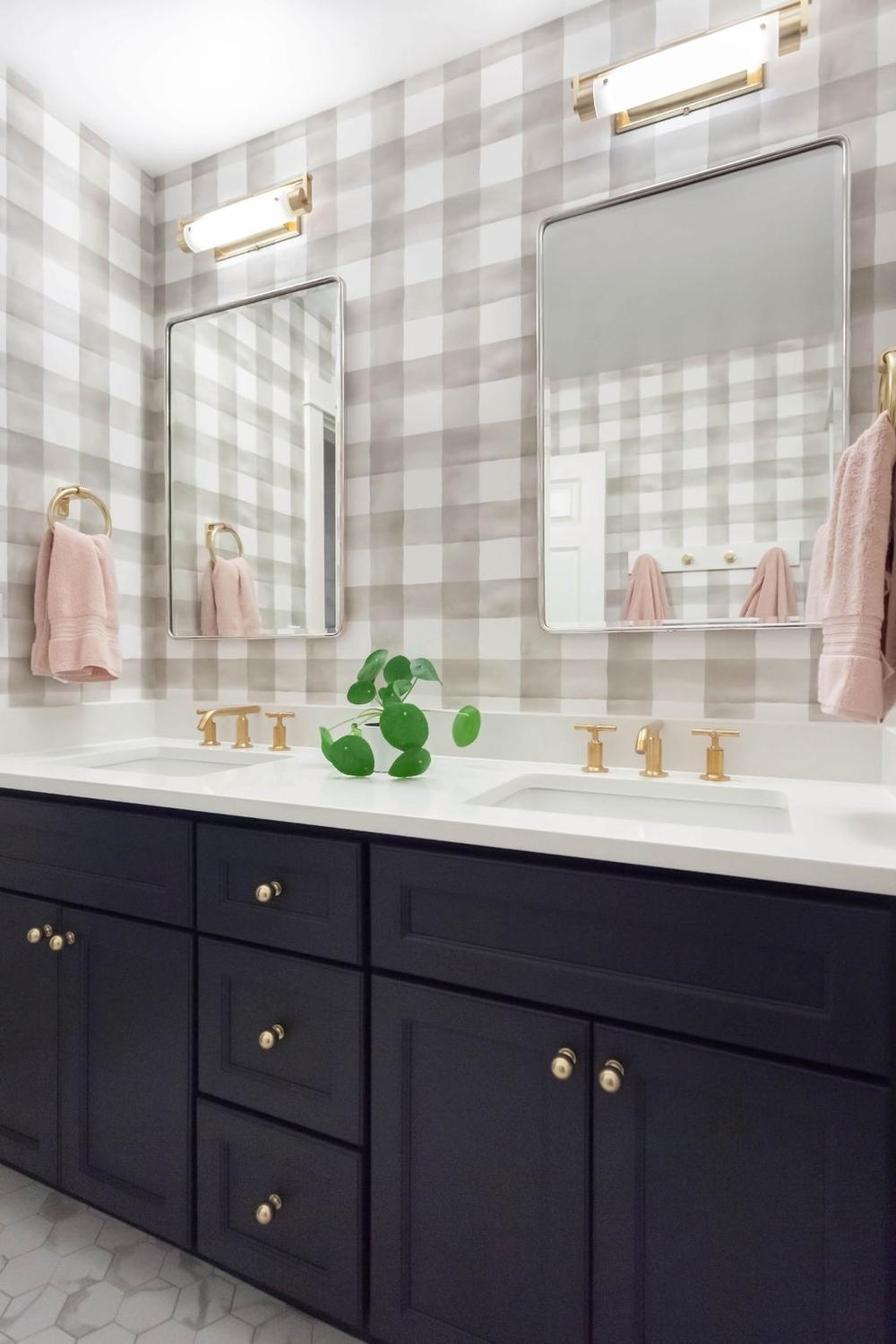 Baño geométrico con papel pintado a cuadros y luces doradas