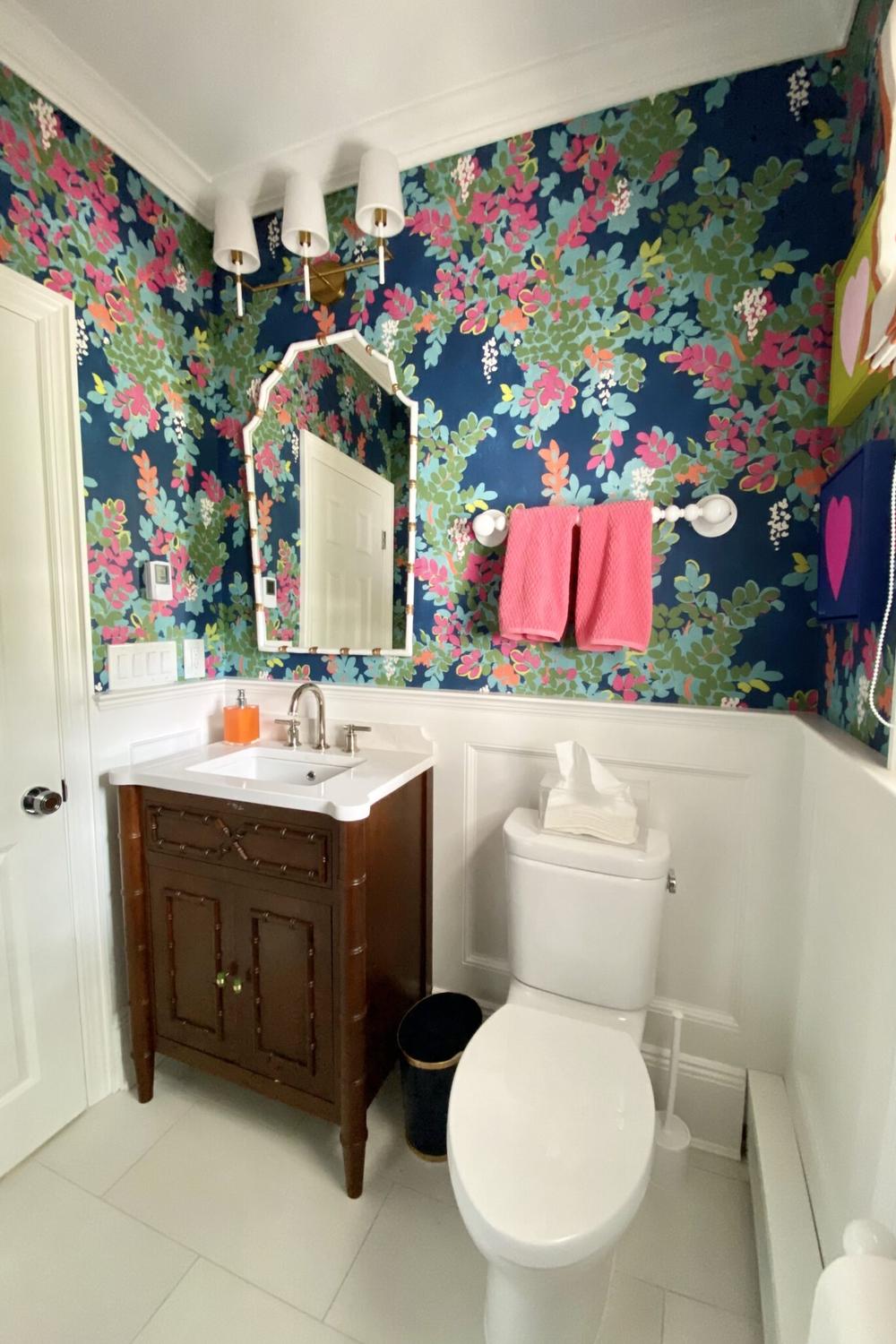 A stylish preppy bathroom with a floral wallpaper and coordinating accessories.