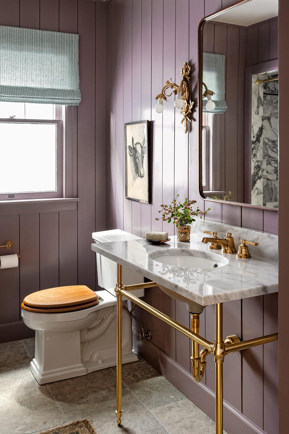 A stylish bathroom with muted purple walls and a marble-topped vanity.
