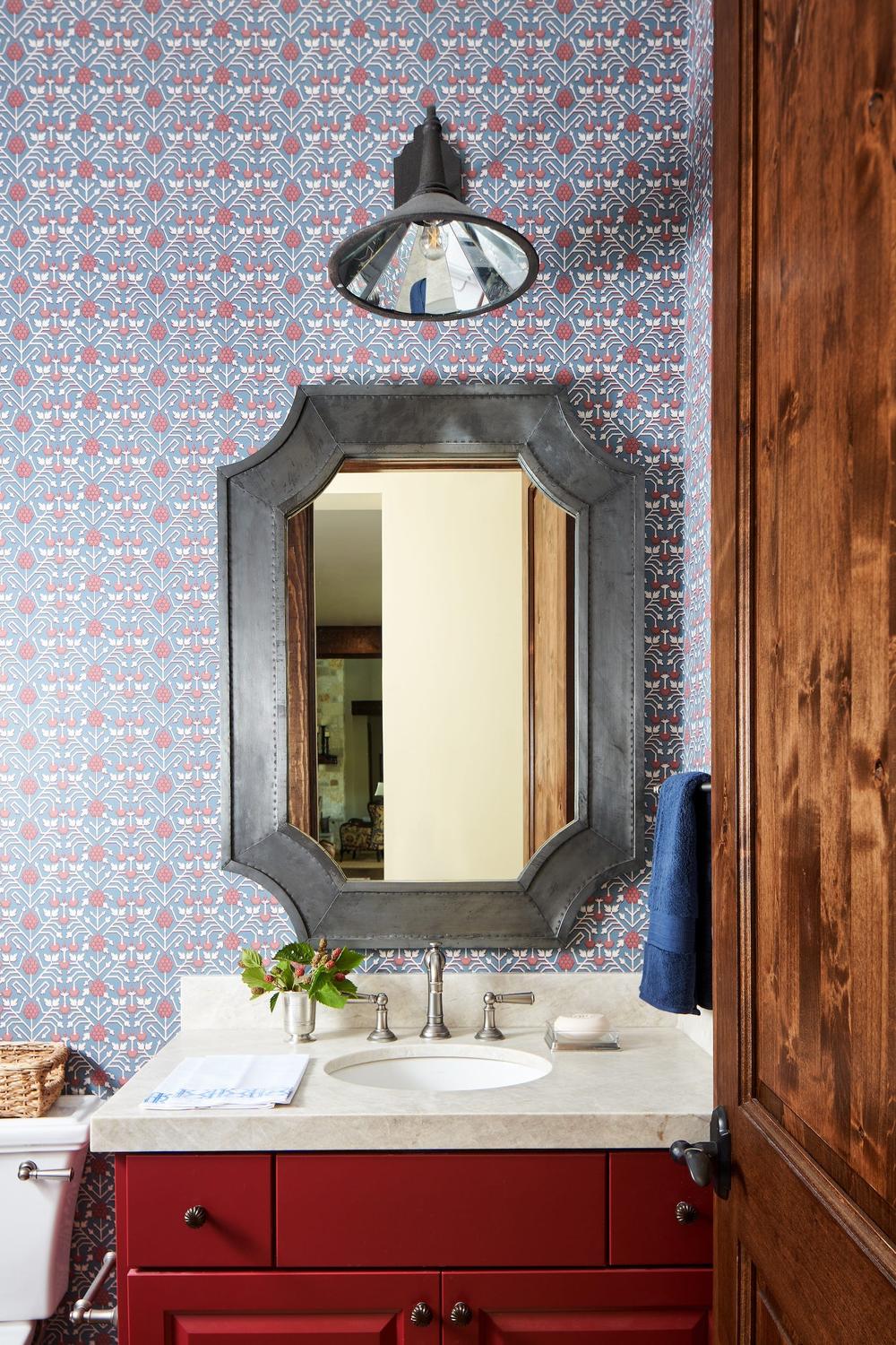 A rich red vanity with a streamlined design and decorative wallpapers.