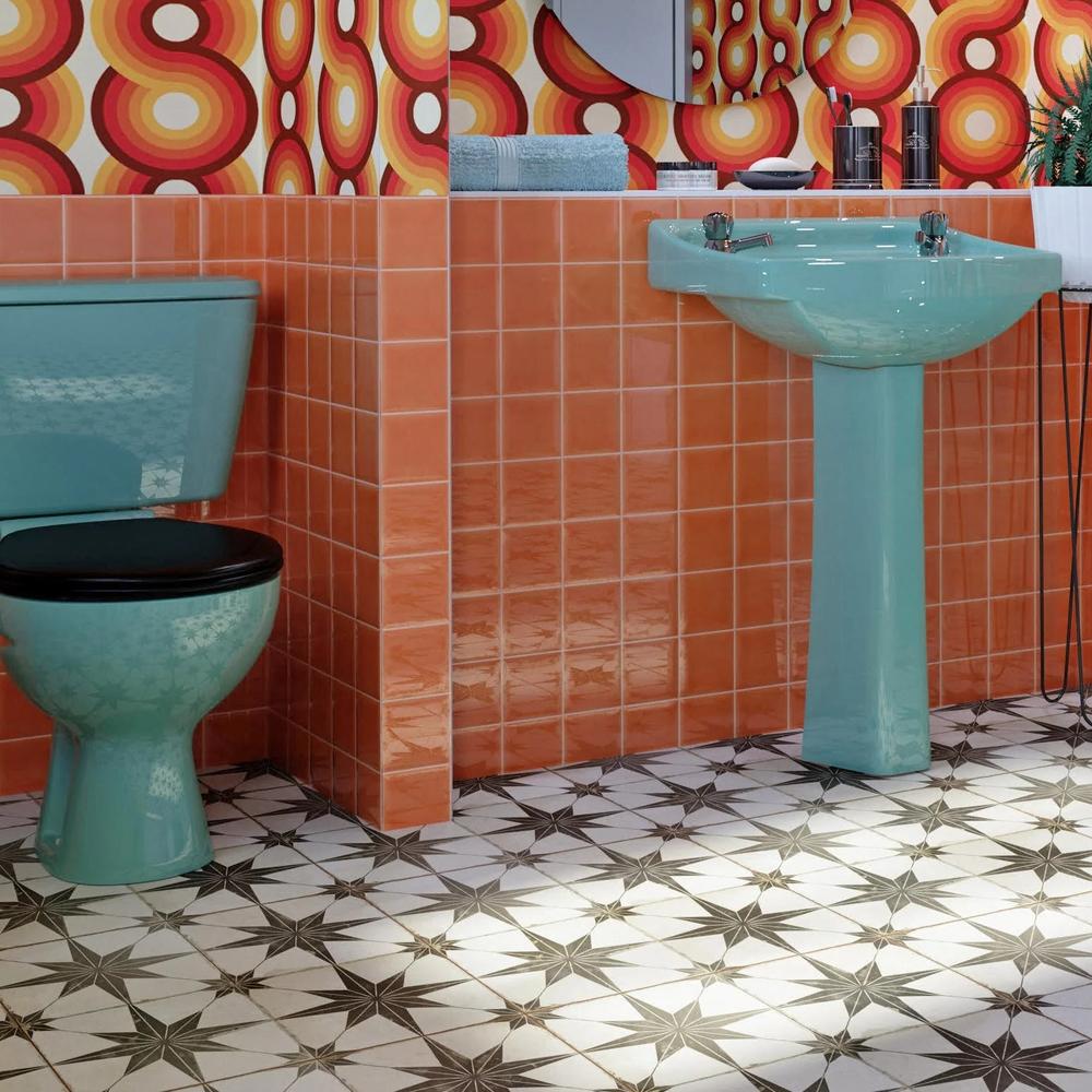 Vibrant retro bathroom featuring bold, circular-patterned wallpaper in warm tones of red, orange, and yellow, showcasing mid-century aesthetics.