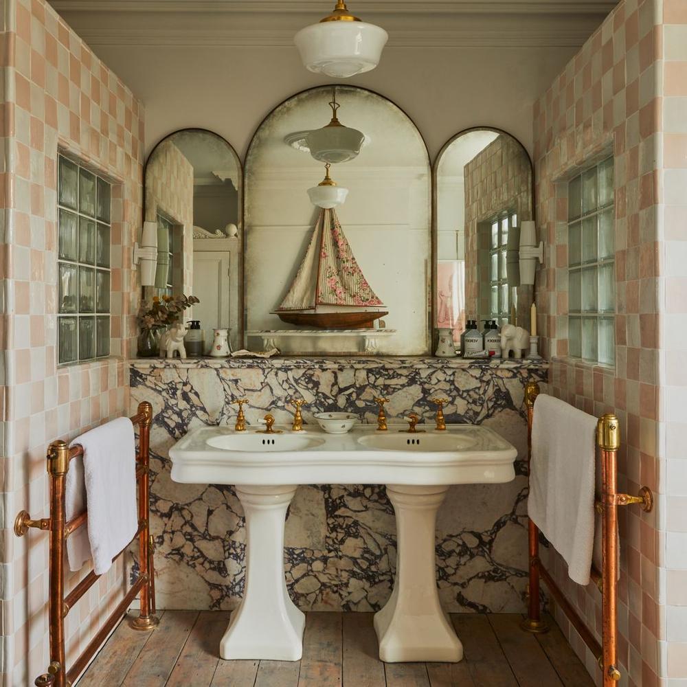 Retro-style bathroom with pastel pink tiles, marble features, double basin sink, and elegant fixtures.