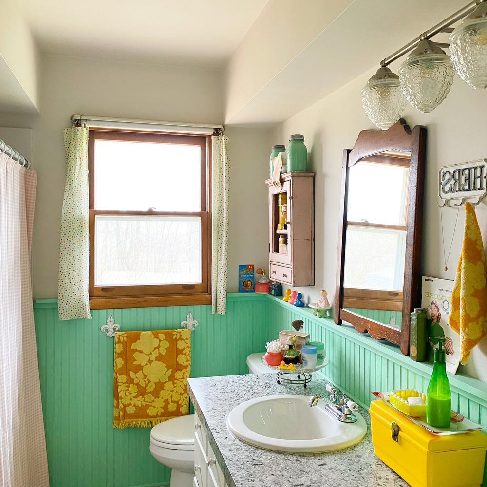 Retro-style bathroom featuring cheerful mint green wainscoting and natural light.