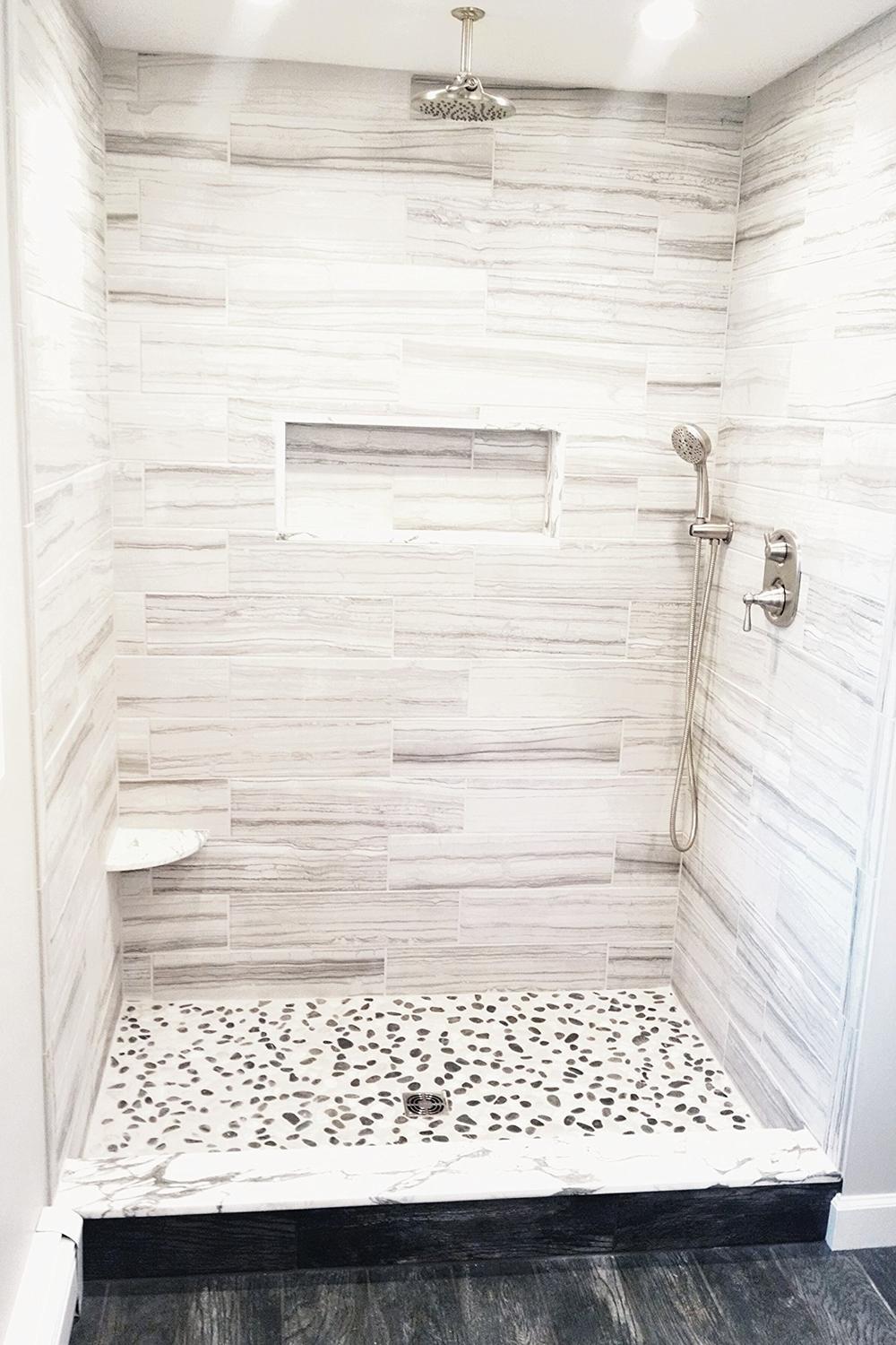 Minimalist shower design with natural rock tiles and elegant fixtures for a peaceful experience.