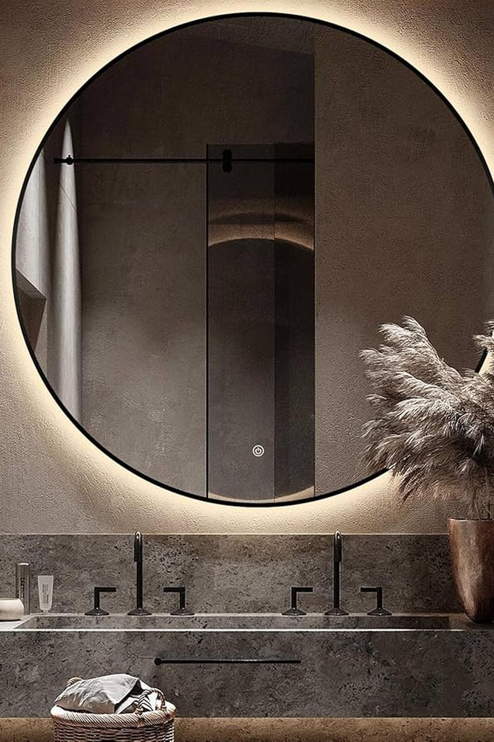 Modern round bathroom mirror with integrated backlighting and sleek vanity area.