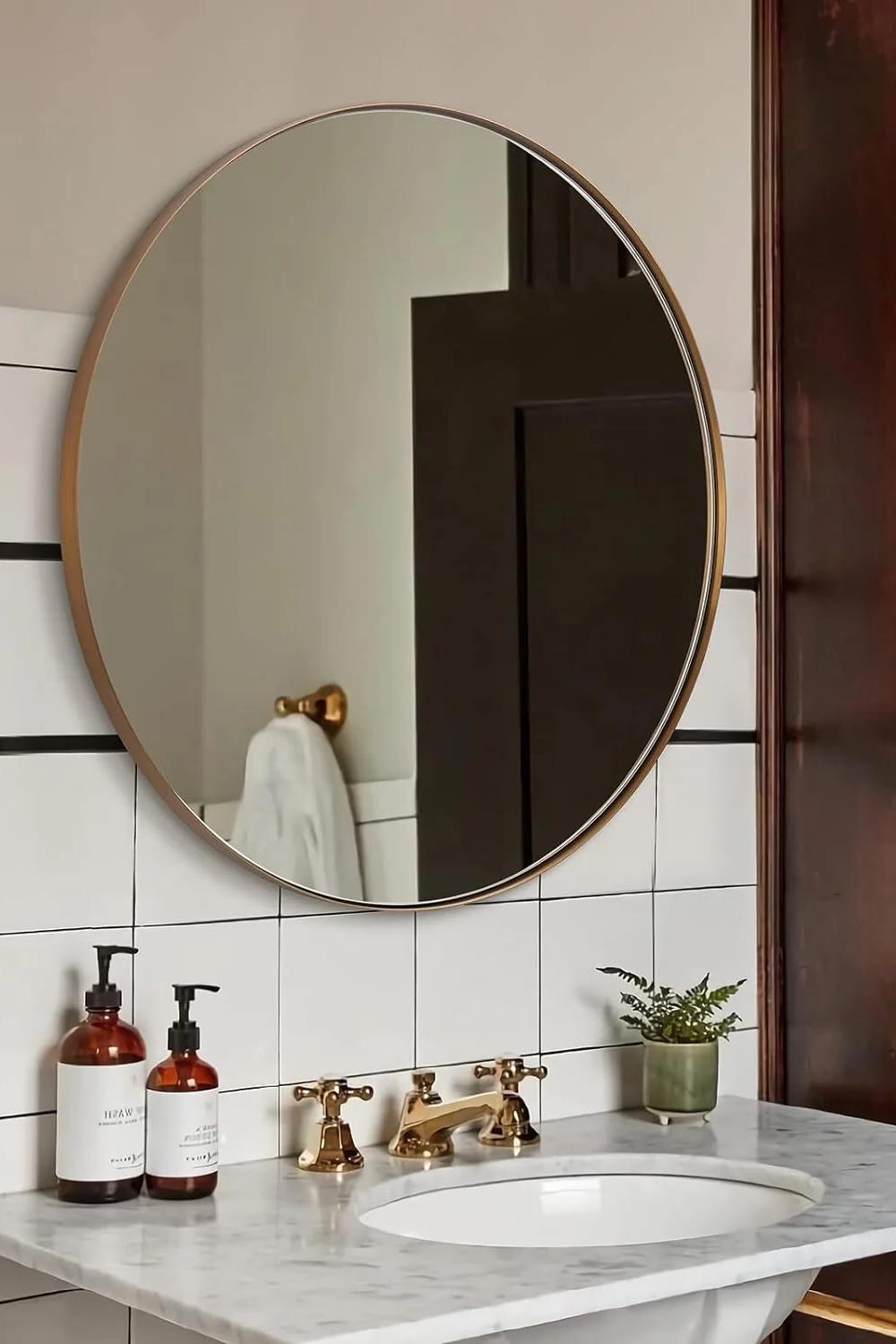 Minimalistic round bathroom mirror mounted on white tile above a luxurious countertop.