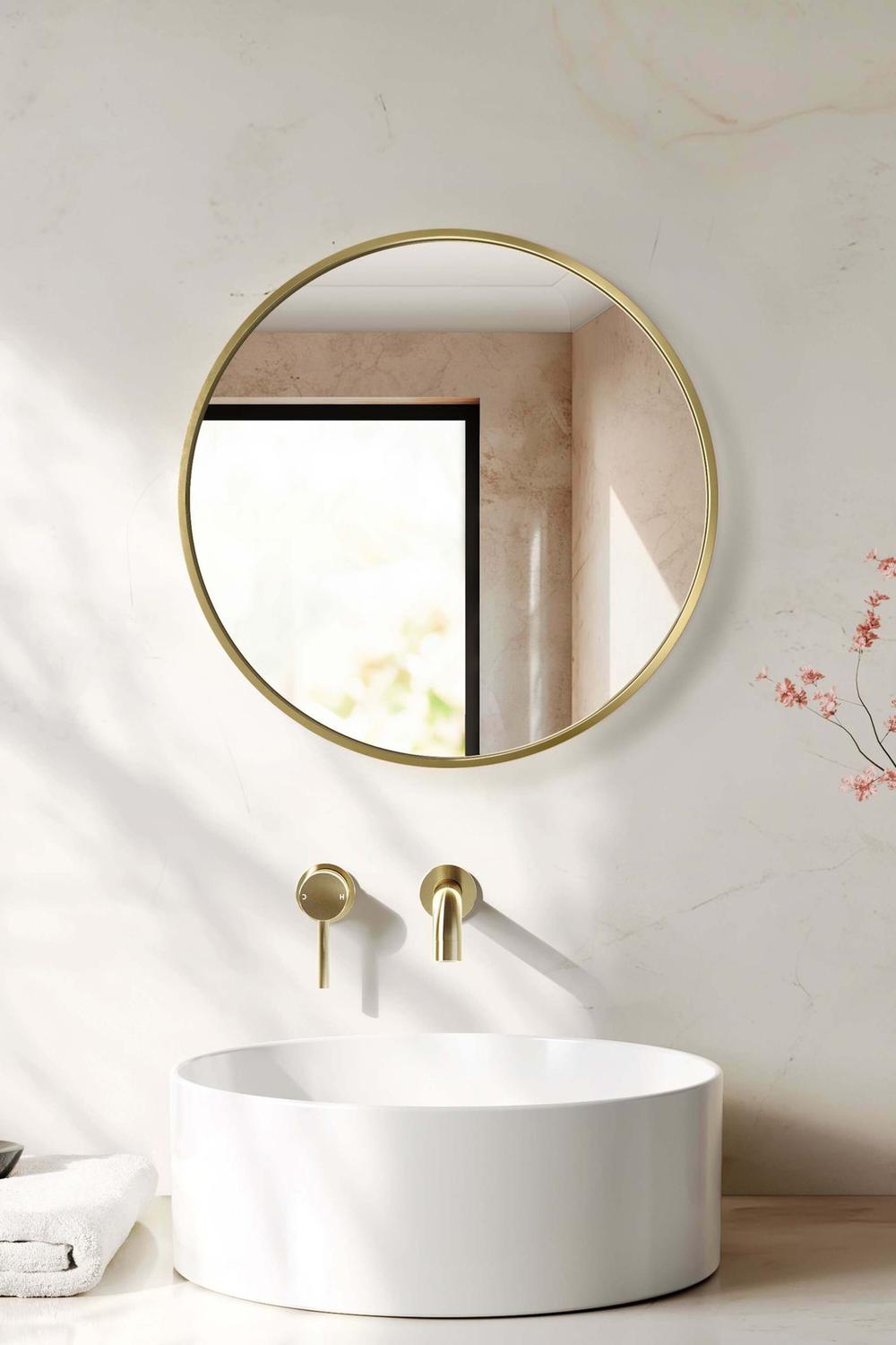 Stylish round bathroom mirror featuring a gold frame and a modern sink.