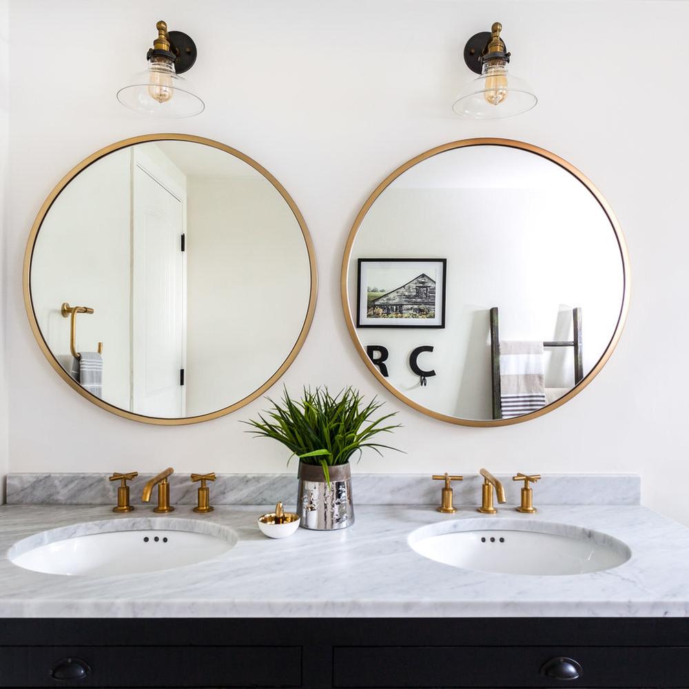 Double round mirrors framing a modern dual sink vanity in a contemporary bathroom.