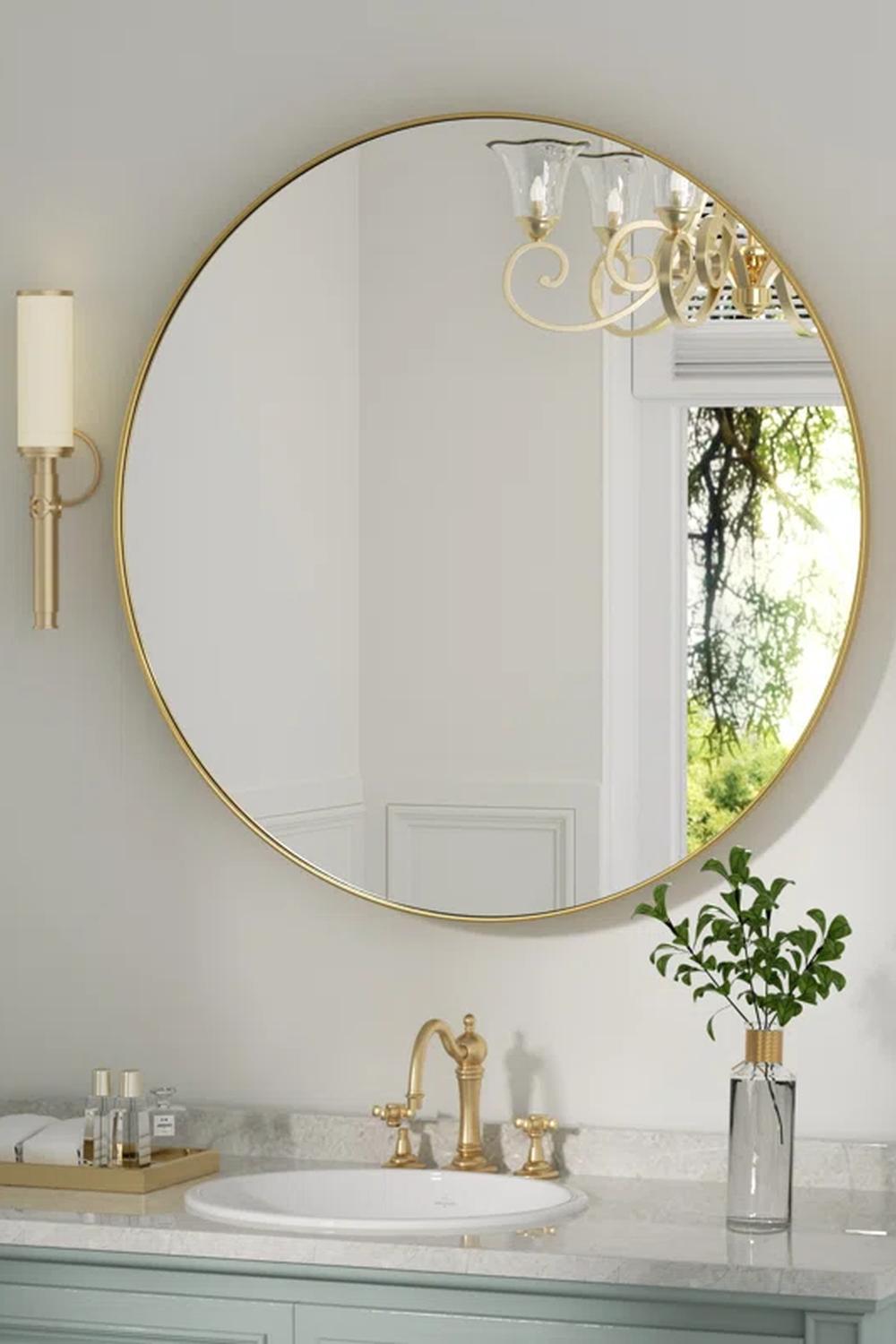 Minimalist oval and round sinks positioned below a chic round mirror.