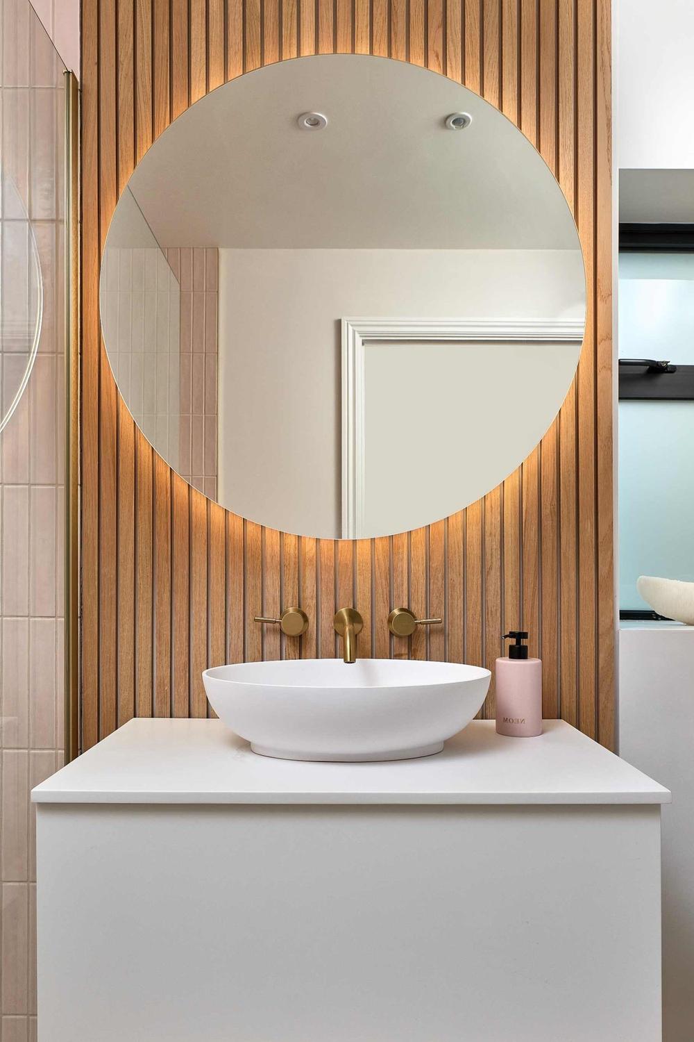 Chic round mirror framed by elegant paneling in an inviting bathroom.