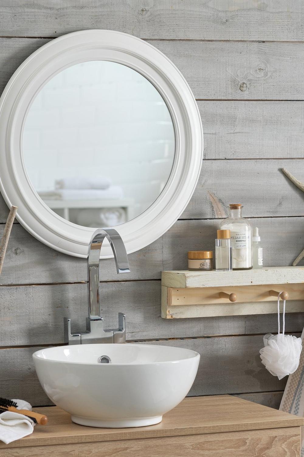 Organic shaped round mirror complementing soft materials in a serene bathroom setting.