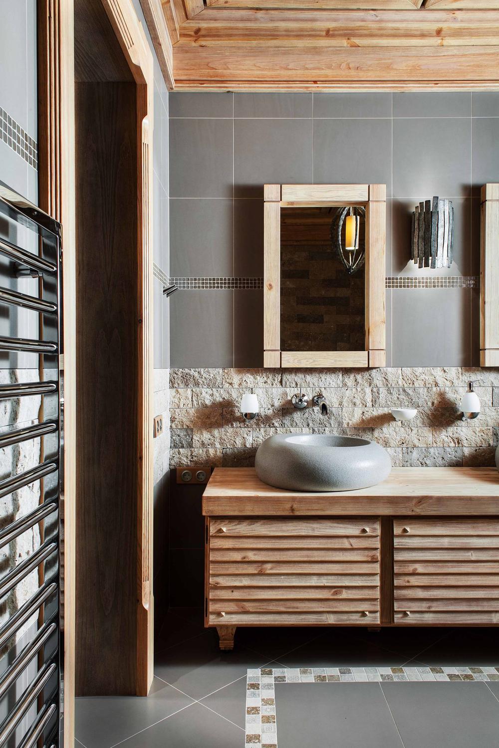 Stylish rustic bathroom with bold red accents and unique stone sinks blending modern and rustic styles.