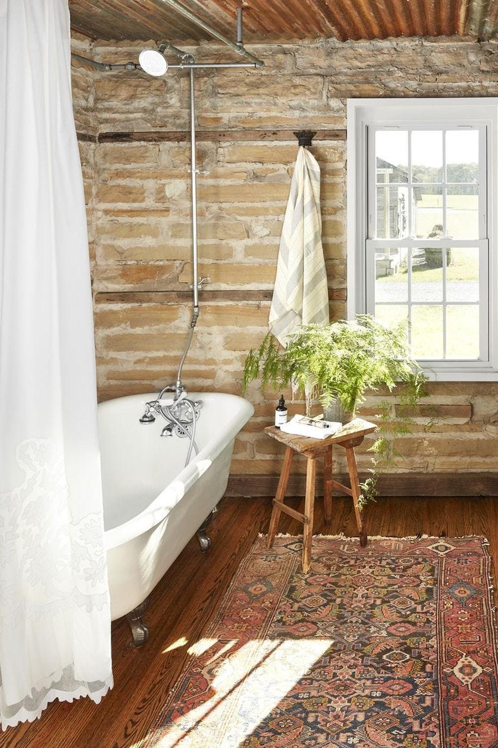 Rustic bathroom with clawfoot tub, ornate fixtures, and nature-like decor.