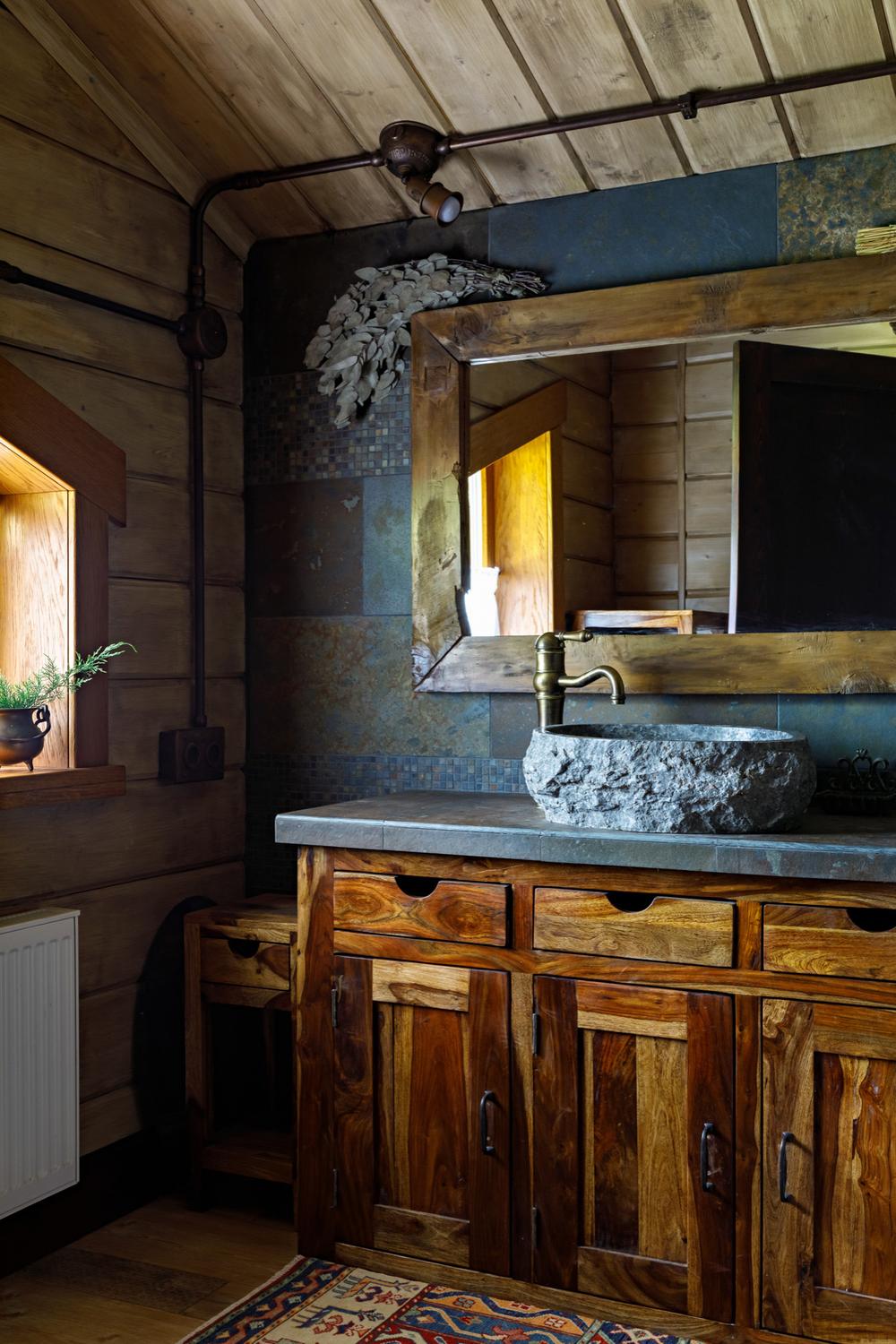 Rustic bathroom featuring wooden elements and a circular stone sink.